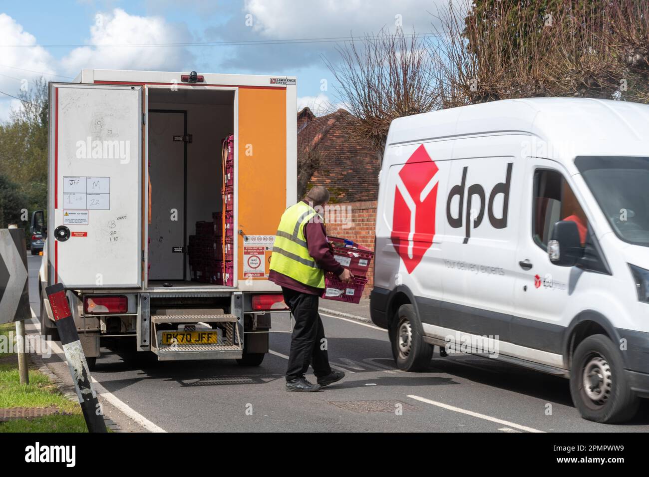 Une fourgonnette de livraison de Sainsbury garé avec le chauffeur livrant des provisions à la maison, tandis qu'une camionnette DPD passe devant, Angleterre, Royaume-Uni Banque D'Images