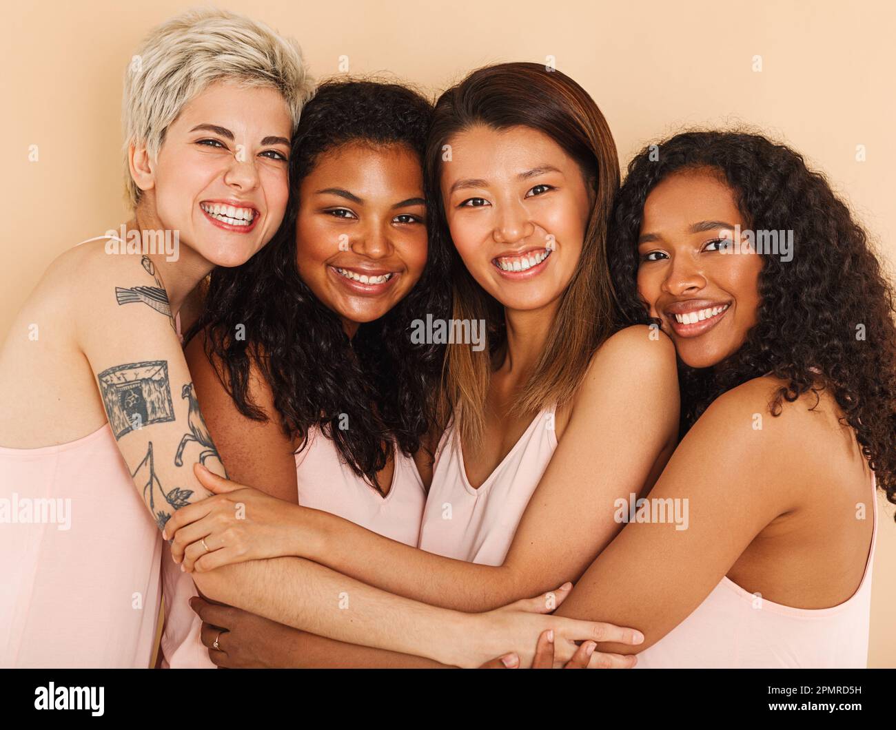 Quatre femmes souriantes et diverses s'embrassent. Groupe de femelles heureuses de différentes races. Banque D'Images