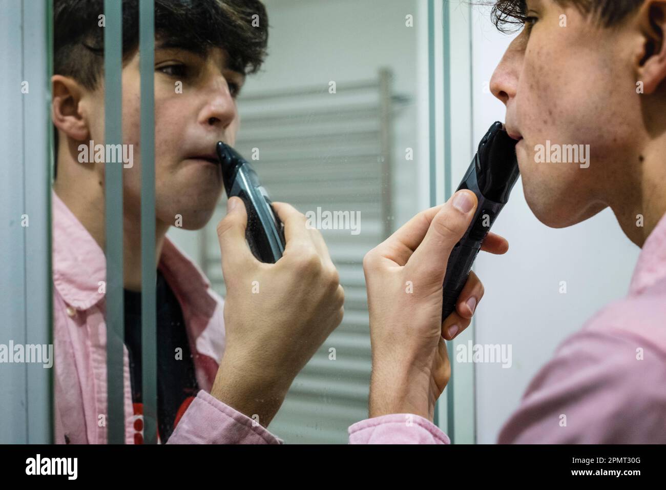 Rasage des adolescents dans le miroir, concentré avec Reflection. Banque D'Images