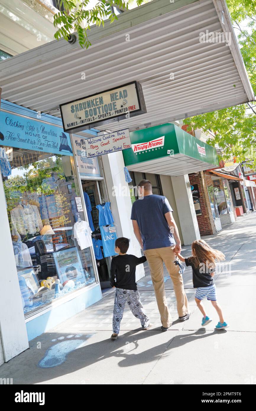 Shrunken Head boutique avec mécanisme UNC. Un homme avec des enfants fait du shopping dans la rue Franklin à Chapel Hill, en Caroline du Nord Banque D'Images