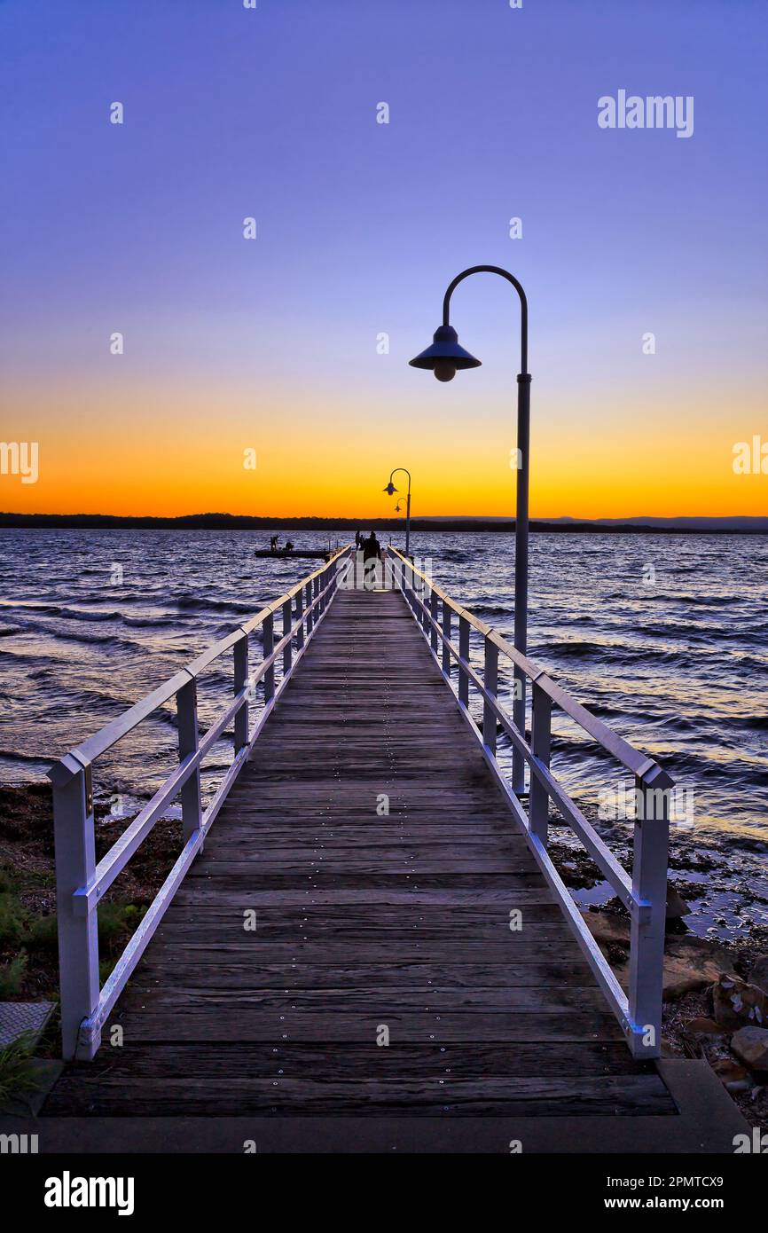 Longue jetée en bois au large de la plage de Murrays Beach sur le lac Macquarie en Australie - pittoresque lakescape. Banque D'Images