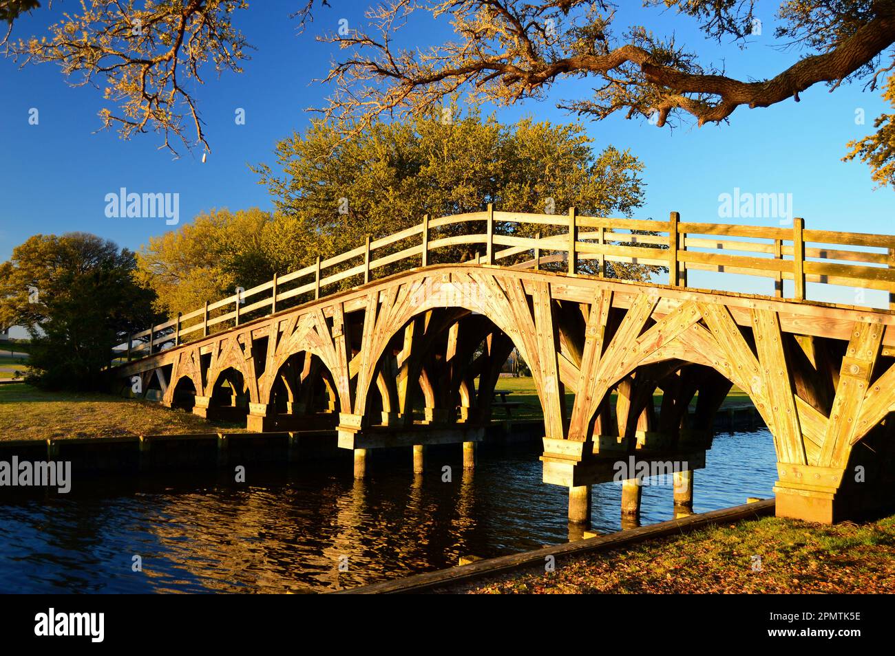 Un pont en bois très orné traverse un petit ruisseau dans un parc public tranquille Banque D'Images