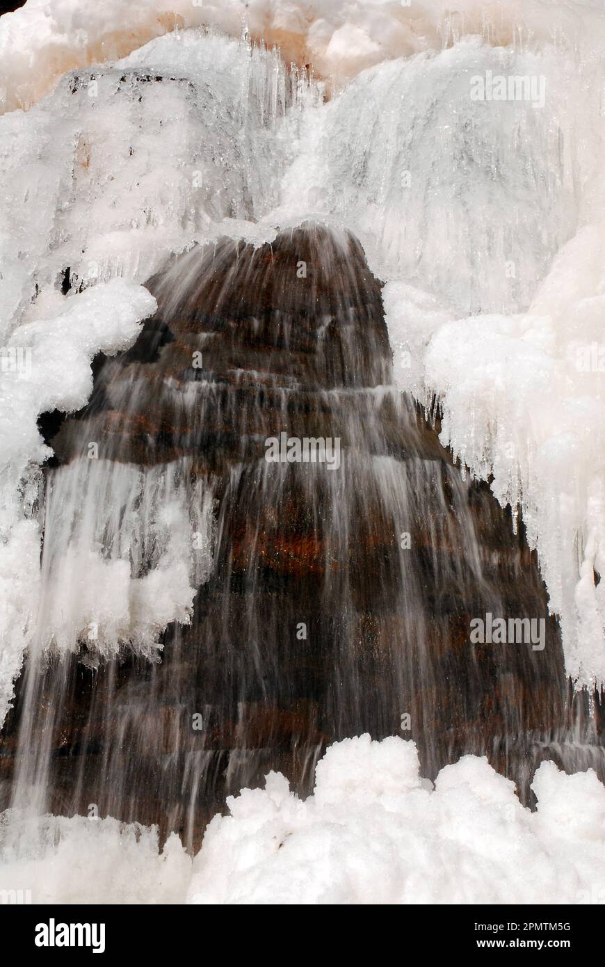 Pendant une journée froide d'hiver, l'eau d'une cascade continue de couler, malgré le gel de la couche de surface Banque D'Images