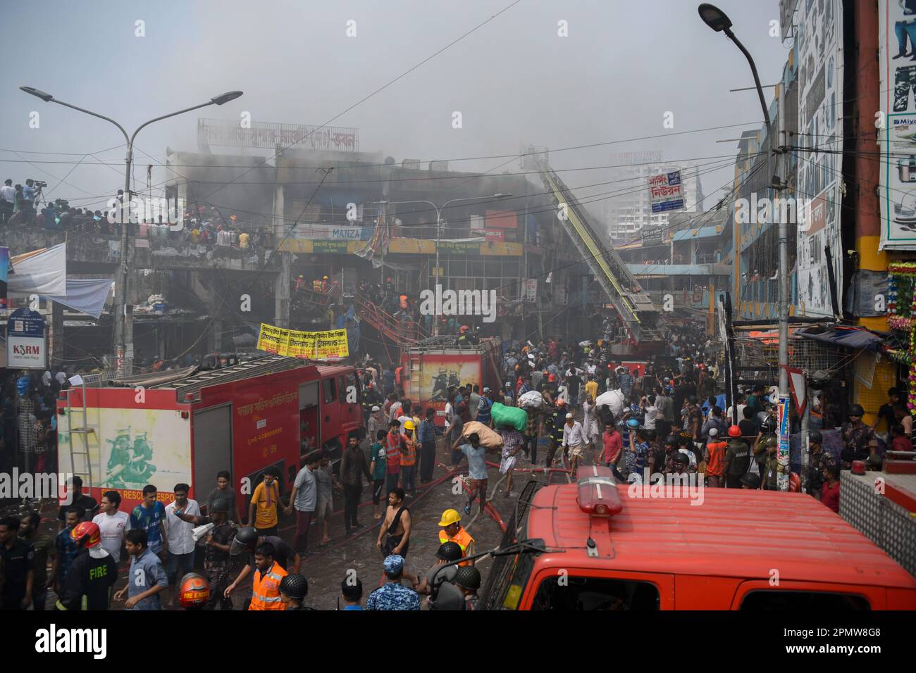 Les pompiers, les secouristes, les gens locaux et les aides travaillent pour éteindre un incendie sur le marché de l'habillement à Dhaka. Un grand incendie a ravagé des milliers de magasins sur un marché populaire de l'habillement dans la capitale bangladaise, Dhaka, où les propriétaires de magasins ont été dévastés par les pertes des semaines précédant l'Eid, le festival musulman marquant la fin du Ramadan. Des centaines de pompiers et de militaires ont lutté contre l'inferno alors qu'il a déchiré le marché de l'habillement, en le transformant en une pile de cendres. Plusieurs personnes ont été blessées, mais aucun décès n'a été signalé jusqu'à présent. Les autorités tentaient toujours de déterminer la cause du Banque D'Images