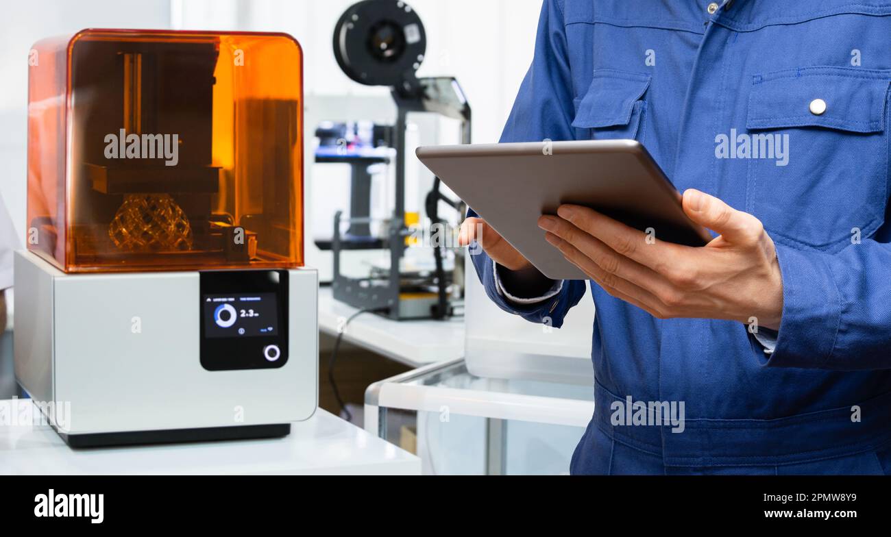 Ingénieur utilisant une tablette numérique pour programmer l'imprimante 3D. Photo de haute qualité Banque D'Images