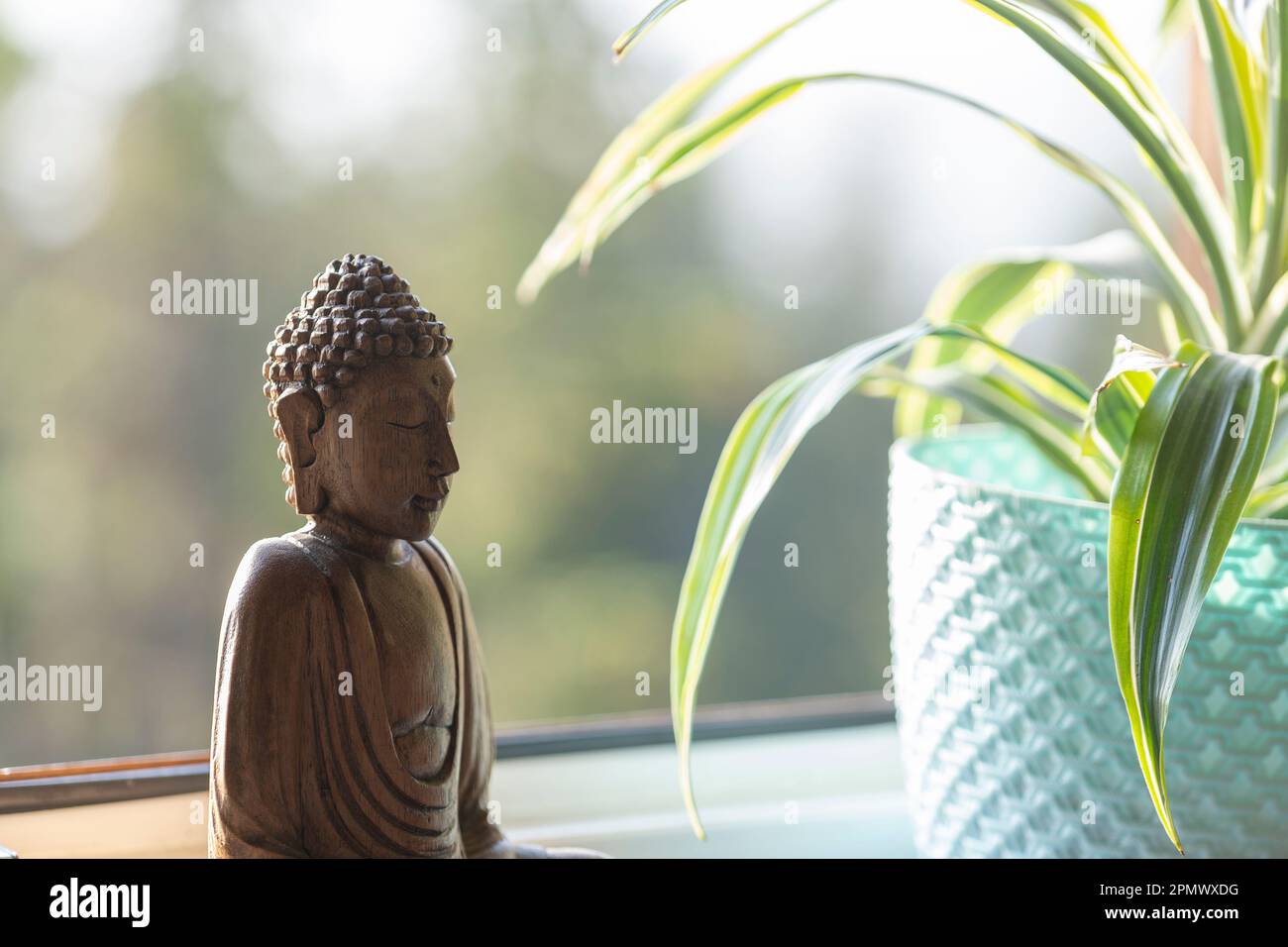 Image en bois de Bouddha sur la fenêtre à côté du pot de fleurs, gros plan Banque D'Images