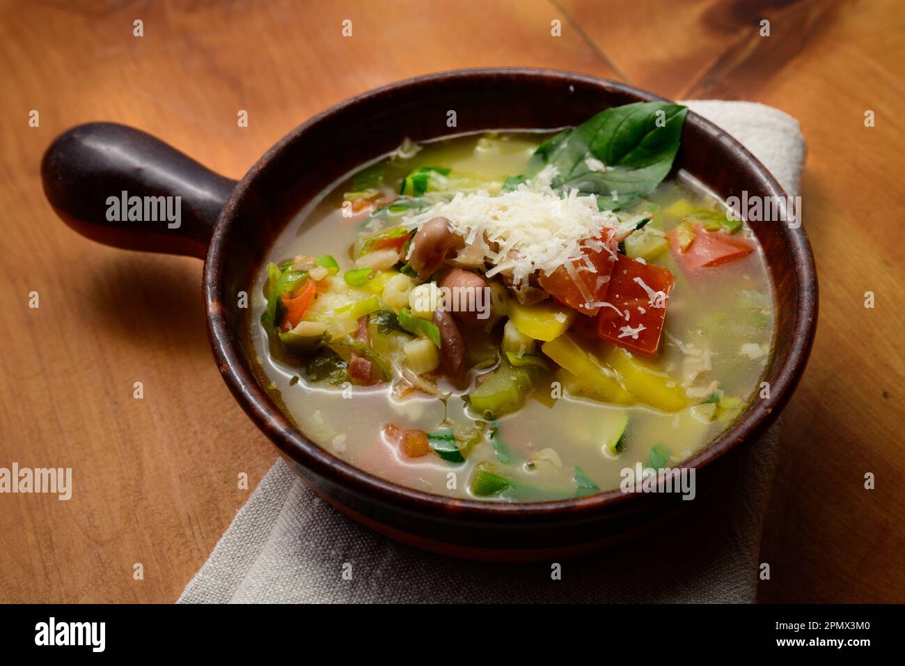 Soupe de légumes italienne minestrone aux haricots et aux pâtes dans un bol rustique en terre cuite avec serviette de table Banque D'Images