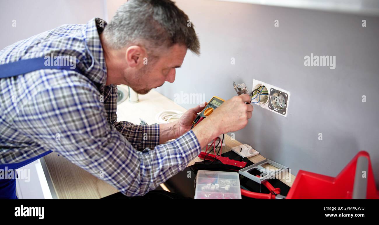 Close-up Of Person Hand Metering Socket Voltage With Digital Multimeter Banque D'Images