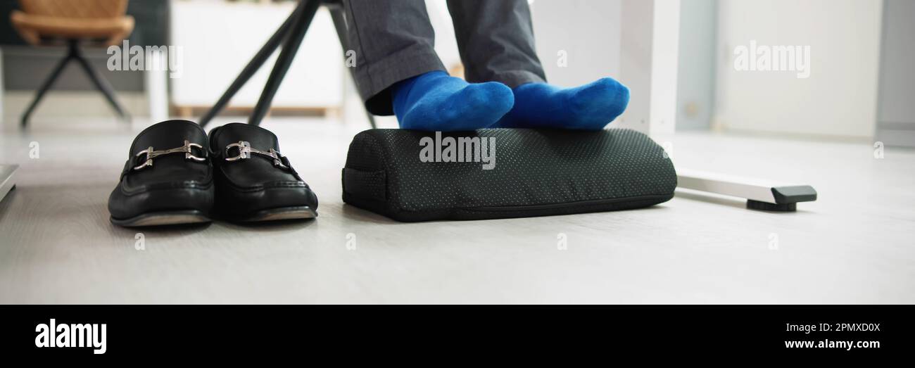 Homme utilisant un repose-pied pour réduire la tension du dos et la fatigue des pieds Banque D'Images