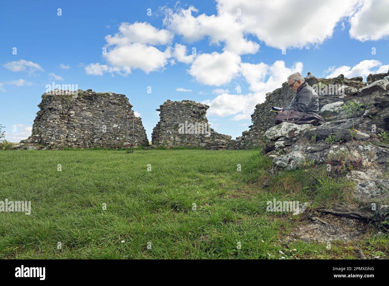 Un visiteur du château de Plympton à Pympton St Maurice, Plymouth, se repose sur une bonne lecture après avoir atteint le sommet de la colline. Banque D'Images