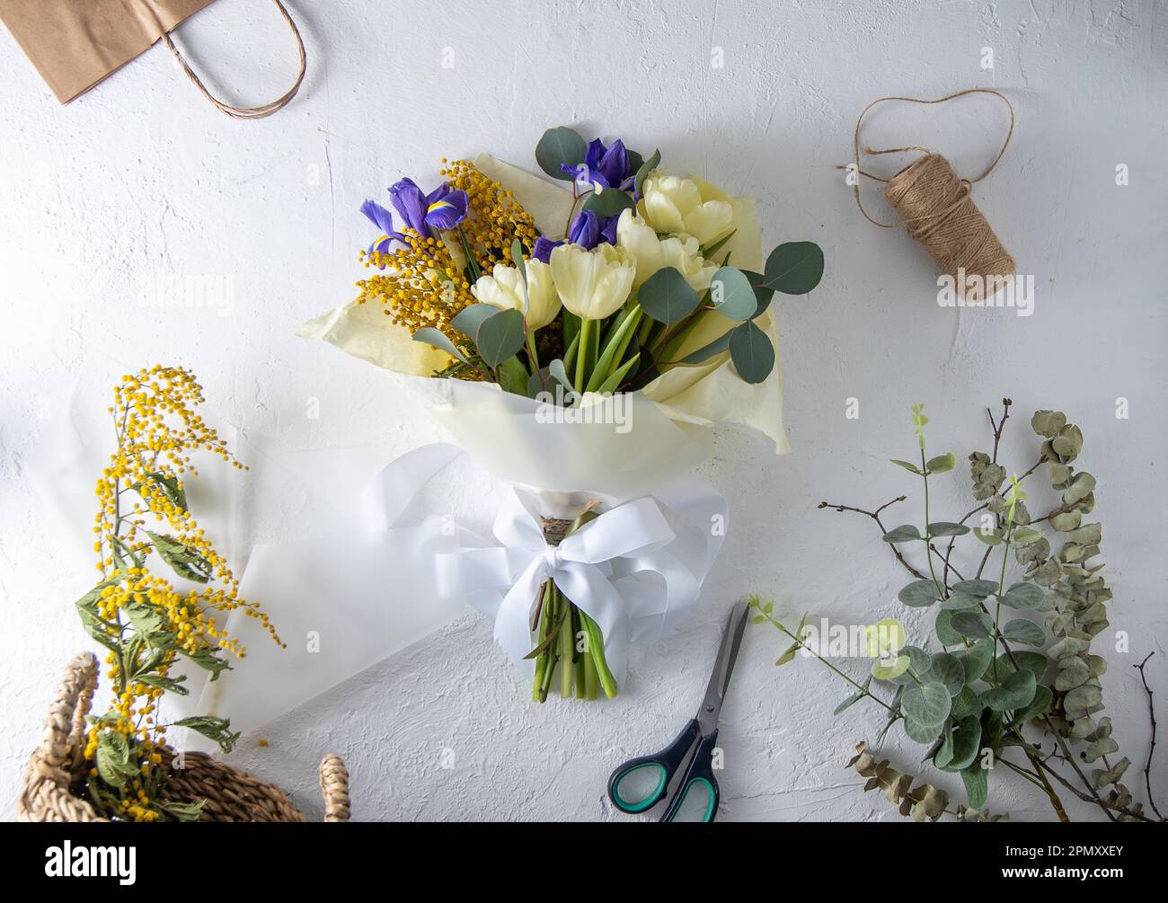 Faire bouquet fleuriste lieu de travail. Arrangement de fleurs dans un  magasin de fleurs. Bouquet de printemps de fleurs jaunes. Iris, tulipes,  mimosa et eucalyptus. Bouton tulipe. Fond floral. Iris violet. Table