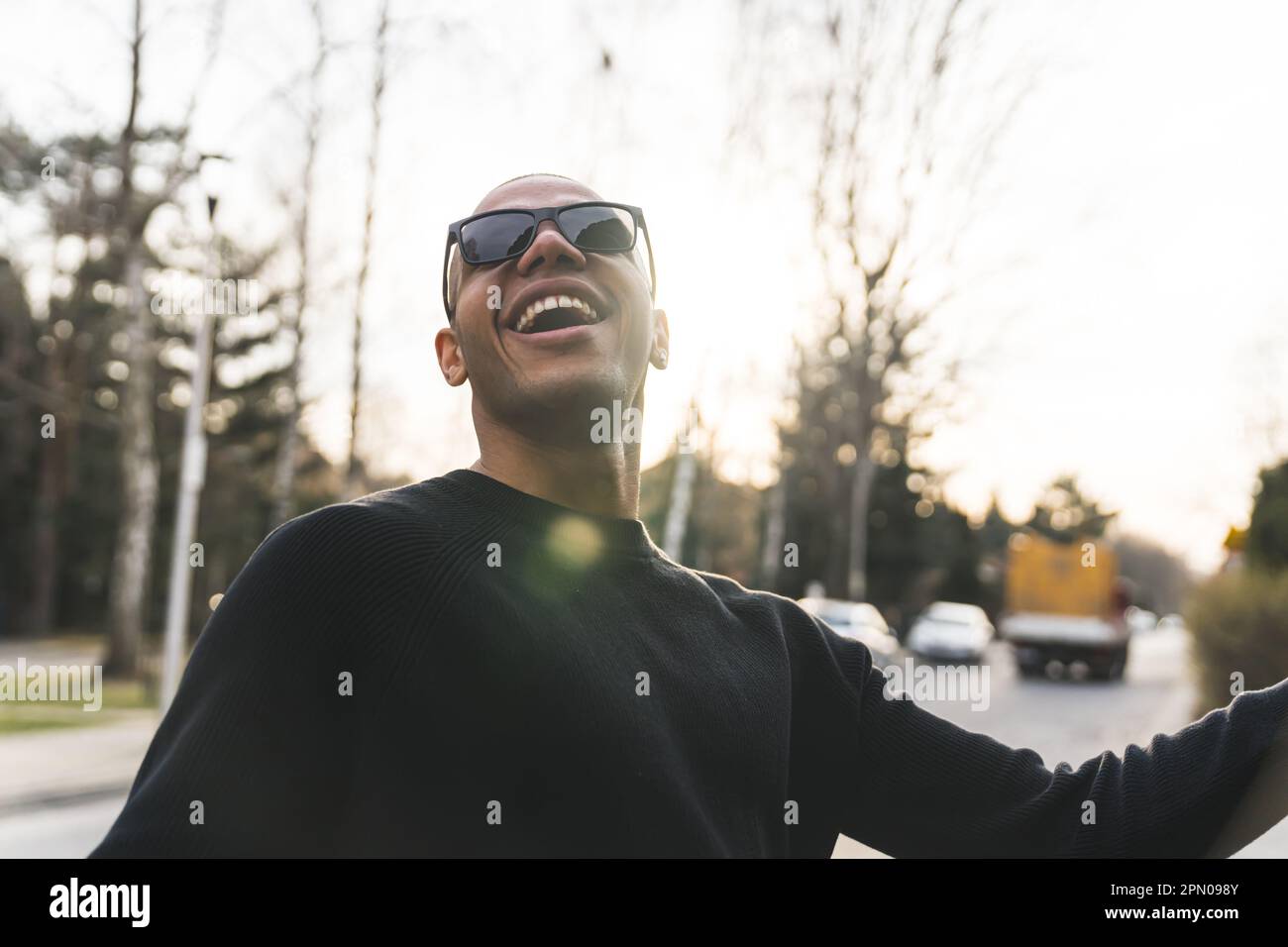 Homme afro-américain souriant en lunettes de soleil debout à l'extérieur  avec son dos au soleil. Photo de haute qualité Photo Stock - Alamy