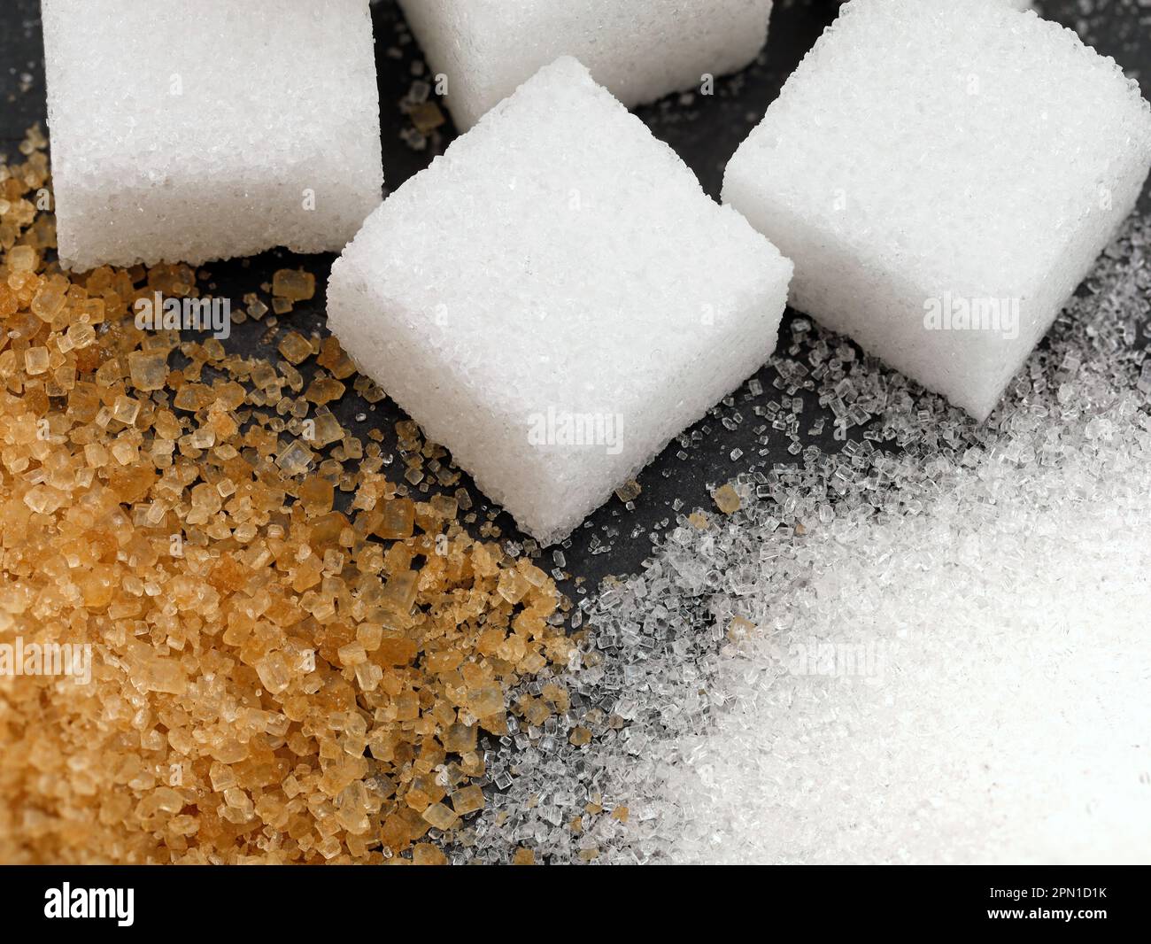 gros plan de trois types différents de sucre, le sucre blanc raffiné en granulés, le sucre de canne brun et les cubes de sucre Banque D'Images