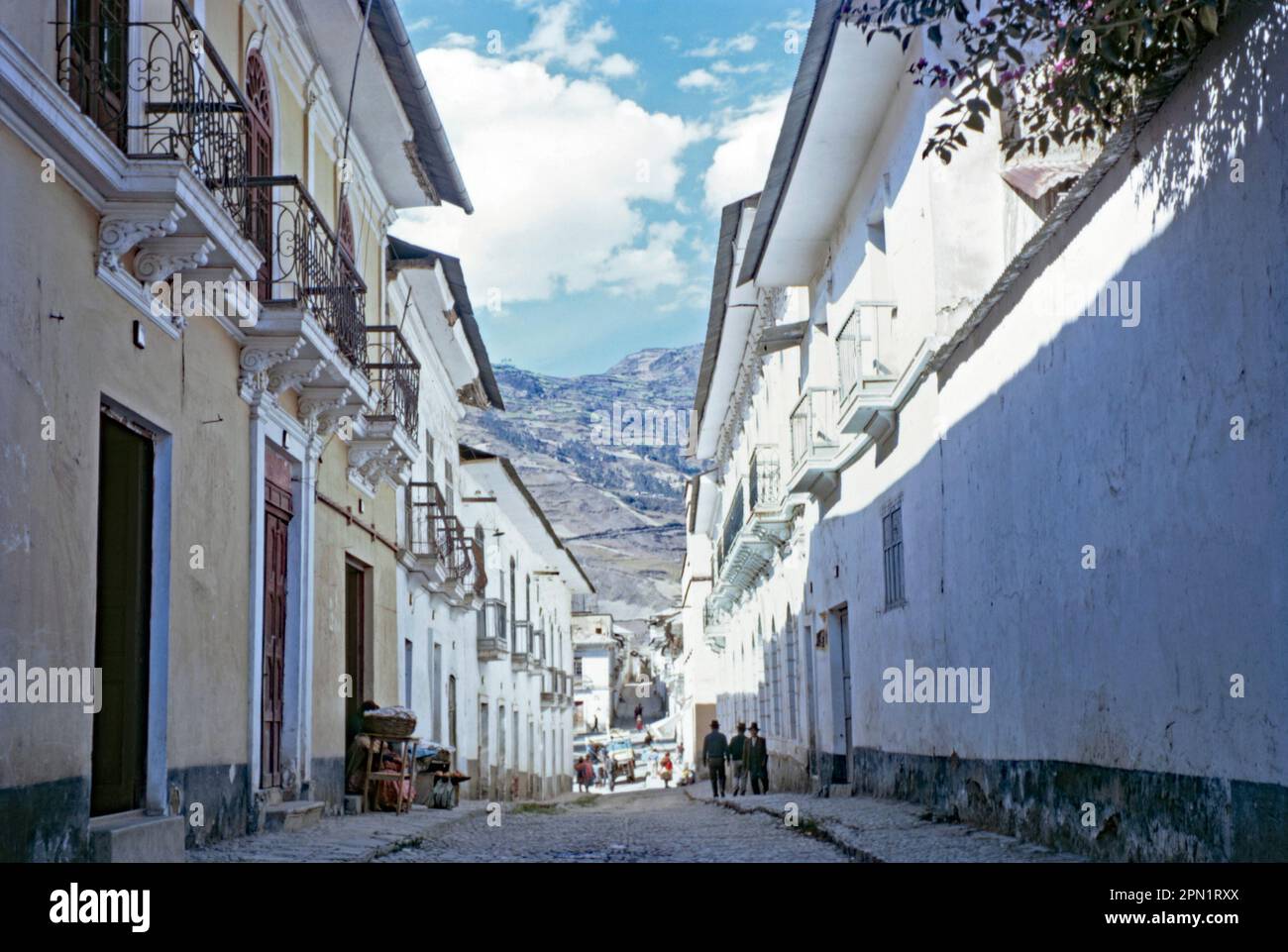 Un petit coin de rue endormi dans la ville de Sorata, en Bolivie, en 1968. L'architecture locale reflète l'influence coloniale espagnole. Les montagnes des Andes s'élèvent en arrière-plan. Sorata est une petite ville dans le département de la Paz dans les Andes boliviennes, au nord-ouest de la ville de la Paz et à l'est du lac Titicaca. Il est devenu un lieu d'escapade de week-end populaire et un point d'arrêt pour les randonneurs - une photographie vintage 1960s. Banque D'Images