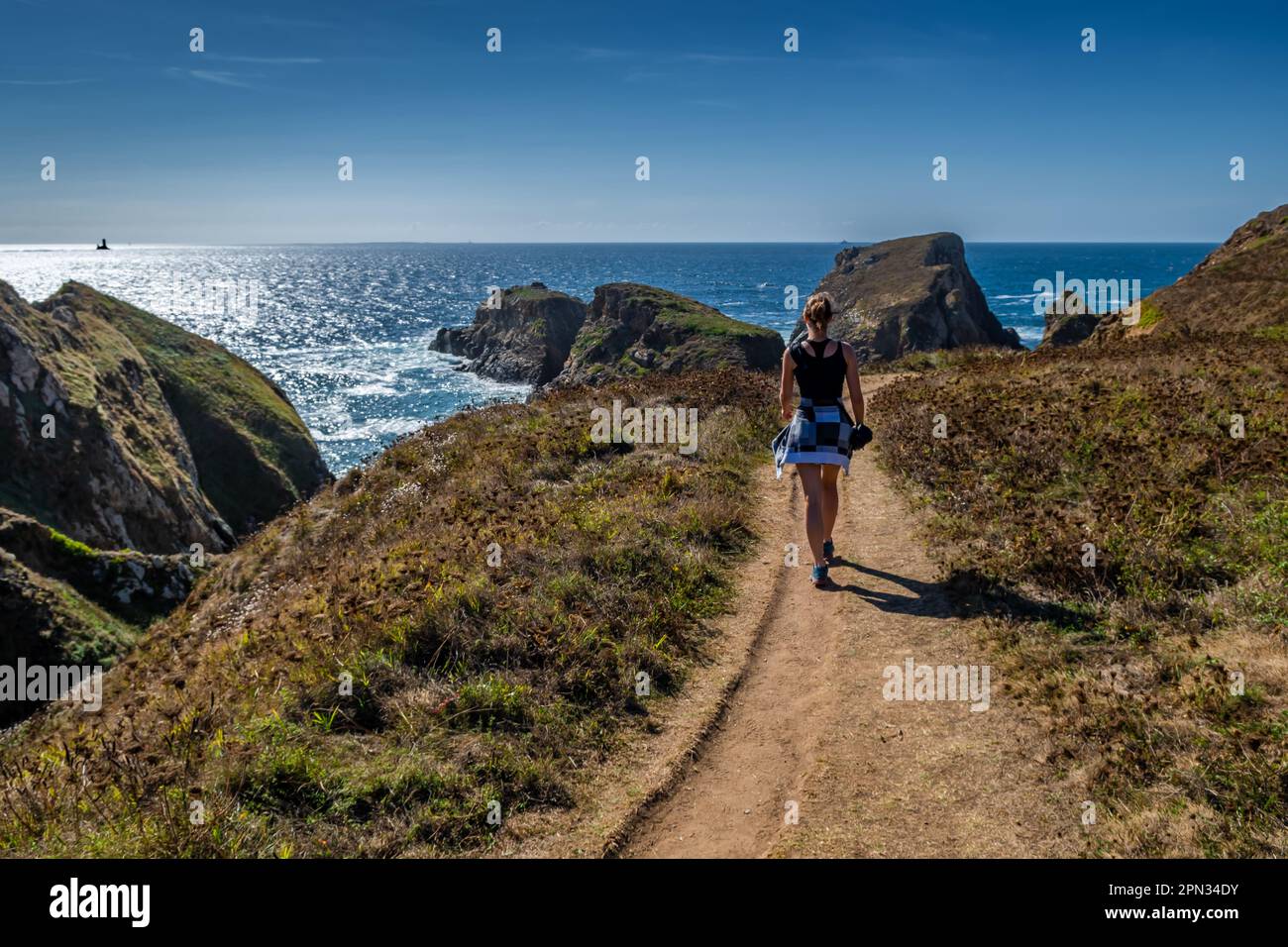 Jeune femme sur le sentier de randonnée côtier avec des falaises spectaculaires à la péninsule de Pointe du Van sur le Cap Sizun sur la côte atlantique du Finistère en Bretagne, en France Banque D'Images