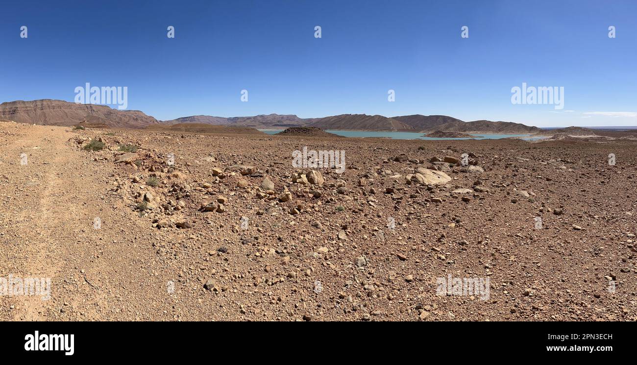 Maroc, Afrique : chemin de terre panoramique et avec en arrière-plan la vue du barrage Al-Hassan Addakhil, un lac bleu clair dans la vallée du Ziz Banque D'Images