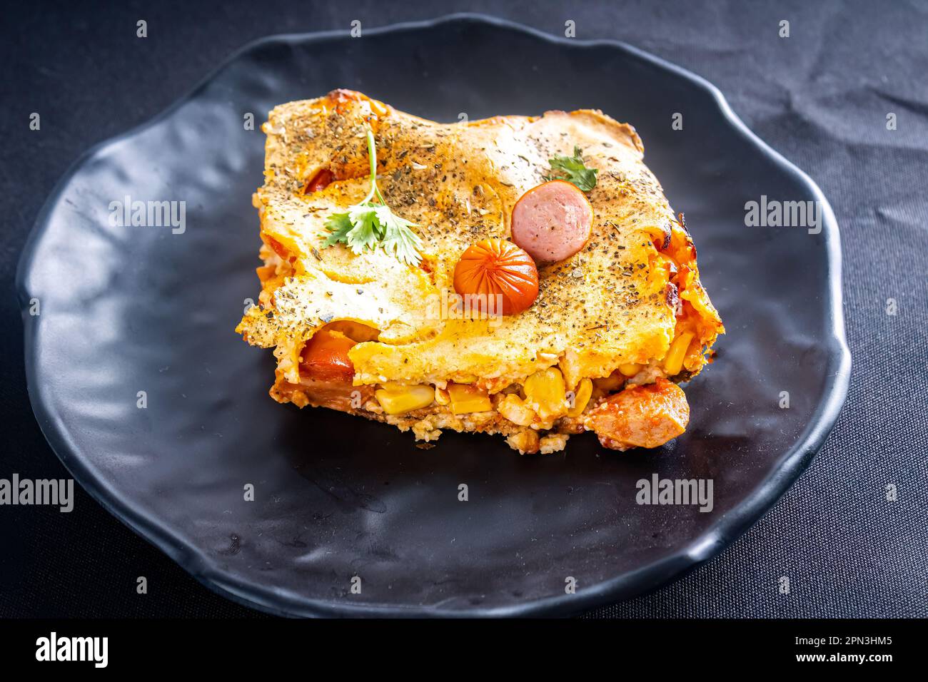 Coupez un morceau de tarte aux saucisses dans un blender, plat typiquement brésilien. Ingrédients : lait, blé, huile, saucisse et maïs. Sur une nappe à carreaux. Perspective v Banque D'Images