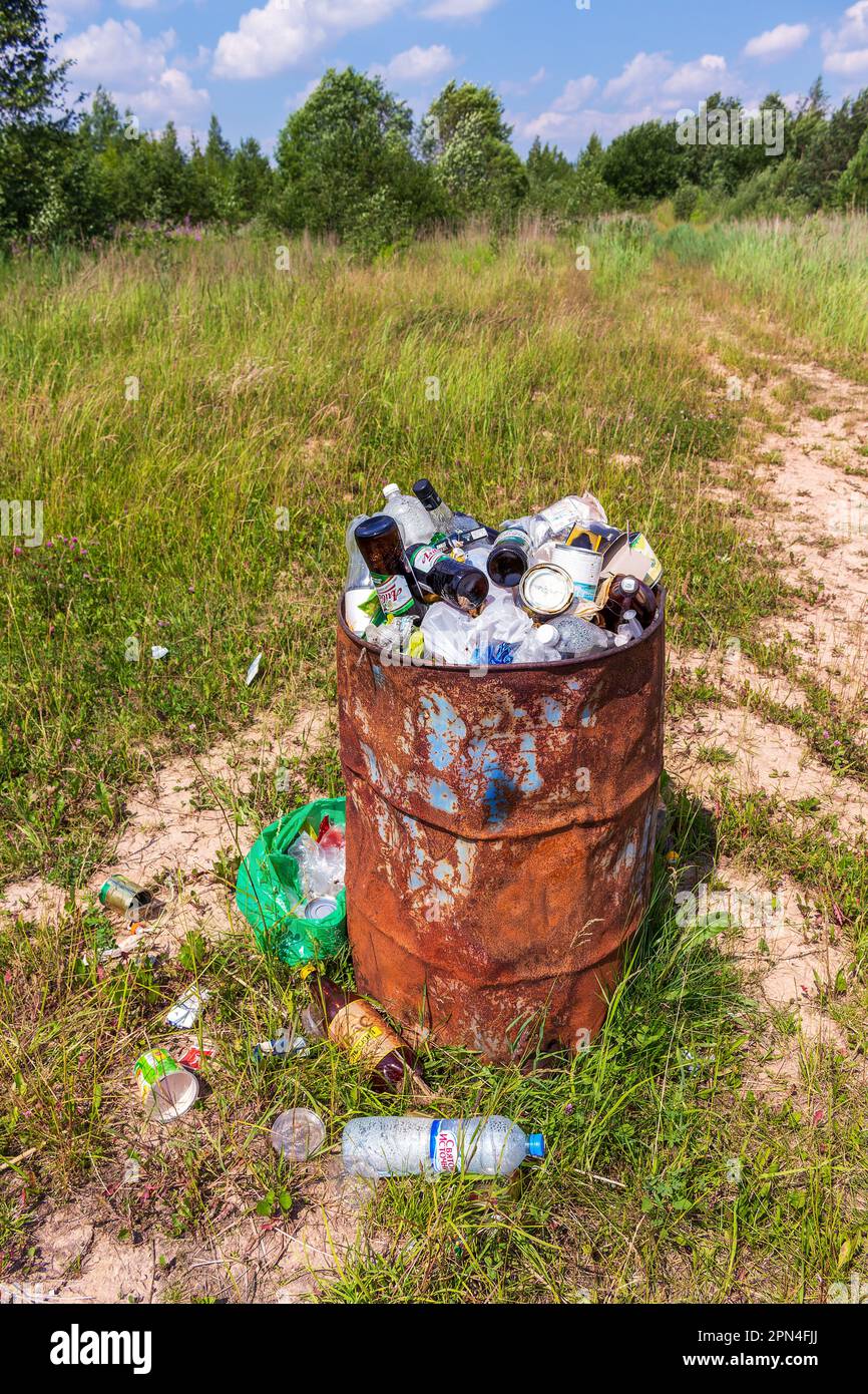 Gros plan d'un baril de métal avec des déchets sur le fond d'une nature immaculée. Pollution de l'environnement par les ordures ménagères. Banque D'Images