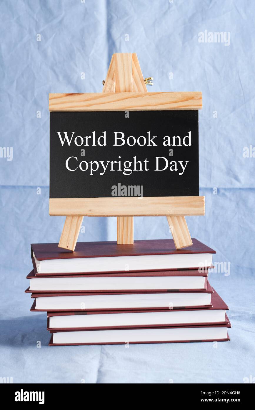 World Book and Copyright Day écrit sur tableau noir sur pile de livres sur fond bleu. réserver des vacances, concept d'éducation Banque D'Images