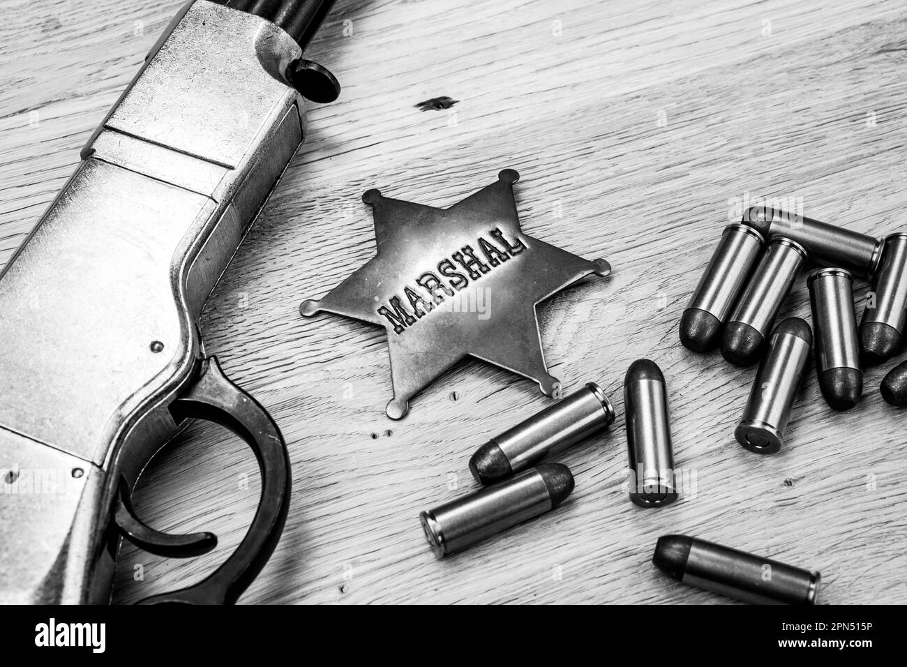 Ancienne carabine à répétition de l'ouest avec munitions et badge de marshals. Photo en noir et blanc. Banque D'Images