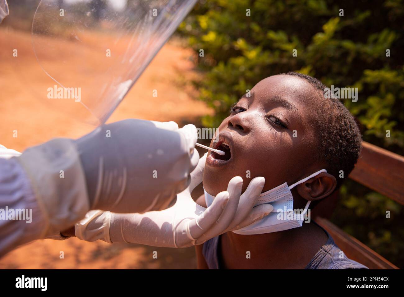 Un médecin effectue un test de coronavirus sur un enfant en Afrique et insère l'écouvillon dans sa gorge Banque D'Images