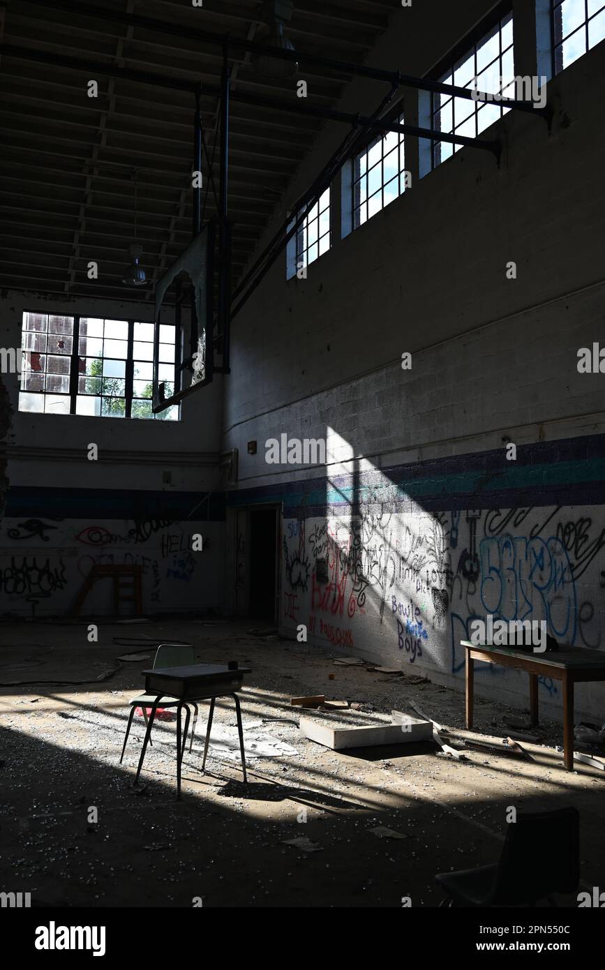 Un gymnase rempli de graffiti et de débris dans une école abandonnée depuis 2001. Banque D'Images