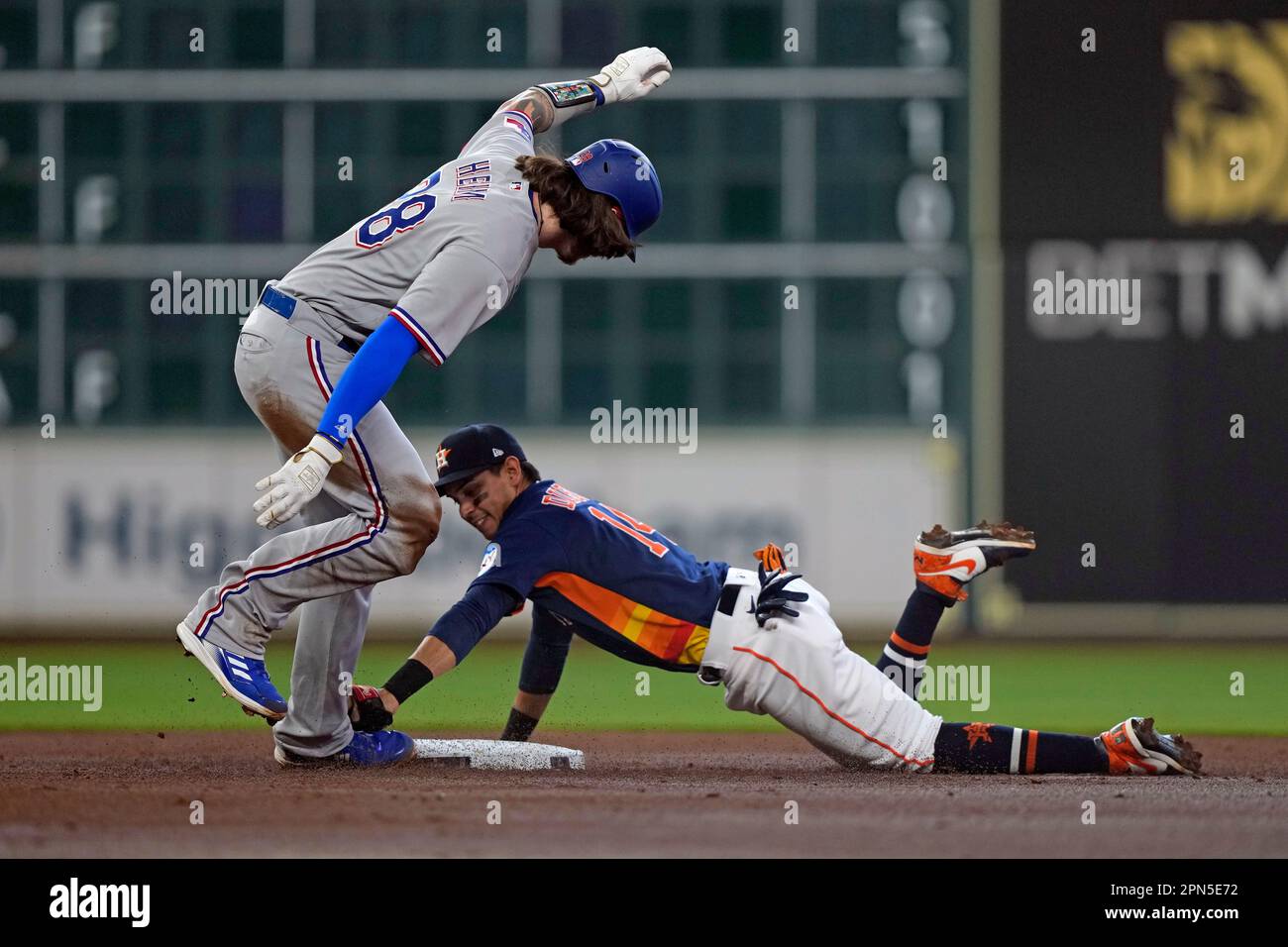 Texas Rangers' Jonah Heim (28) slides into second base after hitting a double as Houston Astros second baseman Mauricio Dubon (14) reaches to tag him during the second inning of a baseball game Sunday, April 16, 2023, in Houston. (AP Photo/David J. Phillip) Banque D'Images