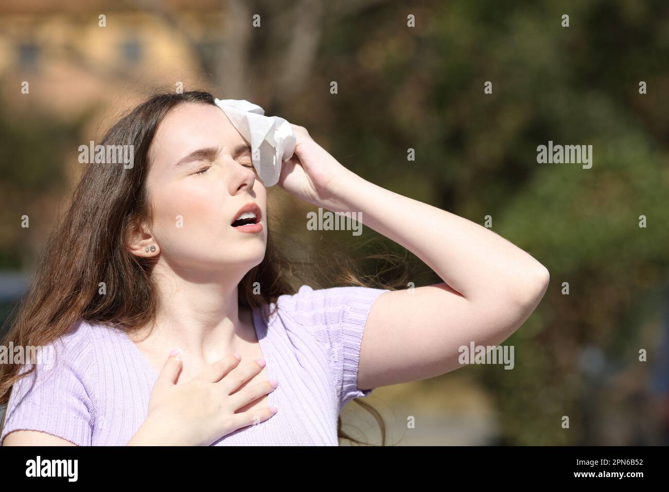 Femme stressée transpirant et séchant avec un tissu dans un parc en été Banque D'Images