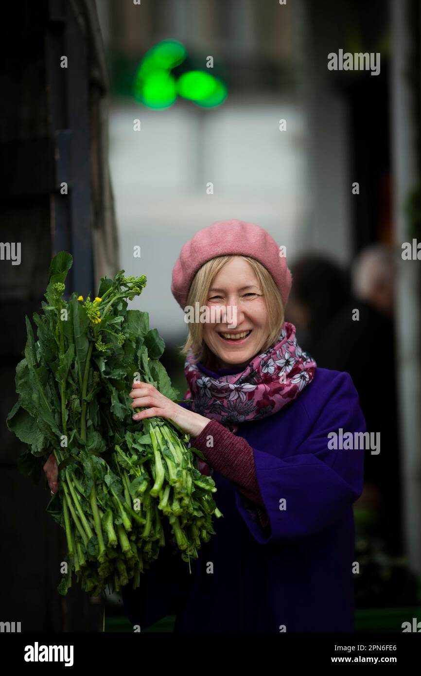 Une femme souriante et heureuse dans un magasin de rue achète et affiche de délicieux greens. Banque D'Images