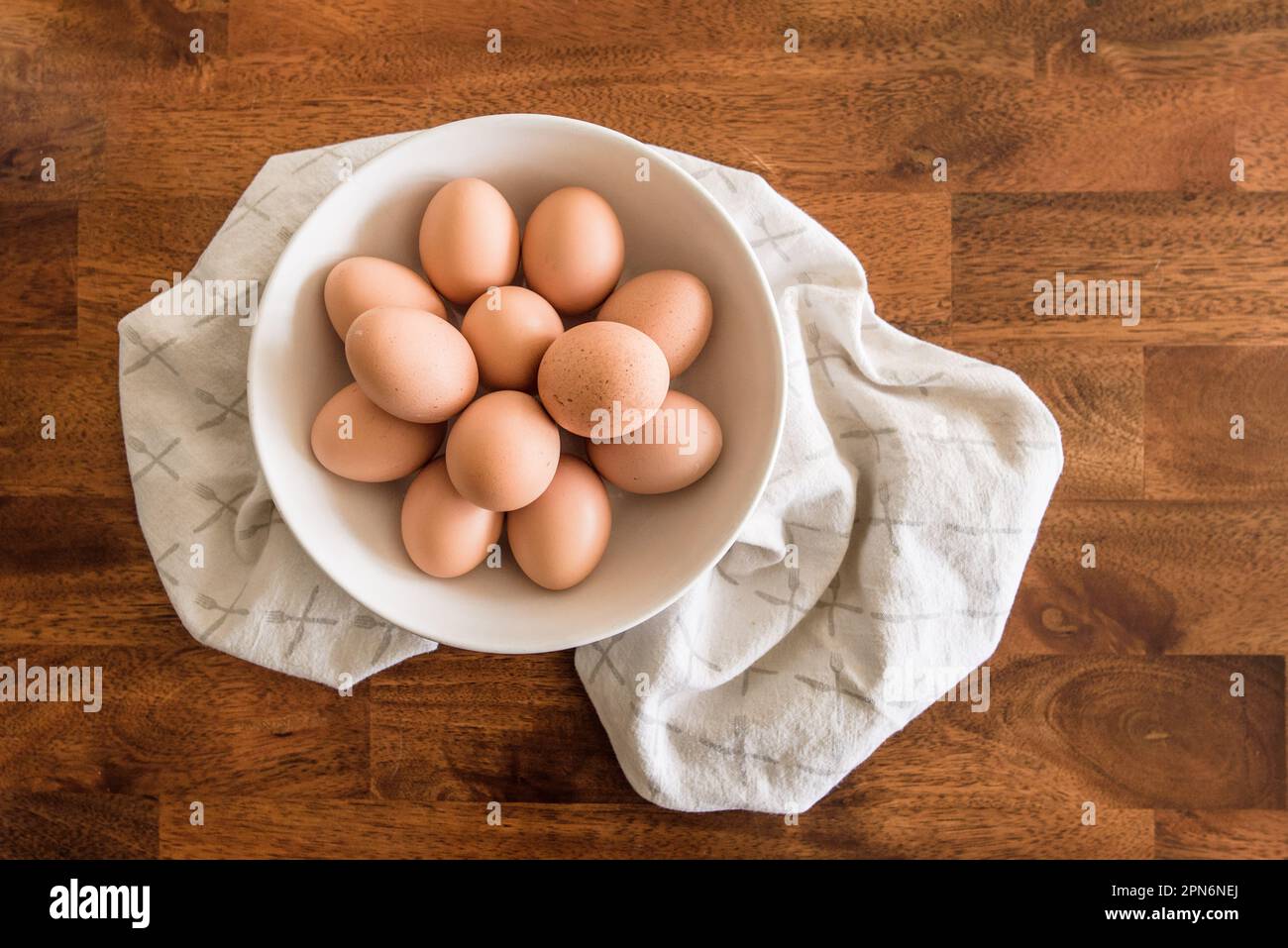 Faire revenir les œufs dans un bol blanc sur une serviette de thé sur une table en bois Banque D'Images