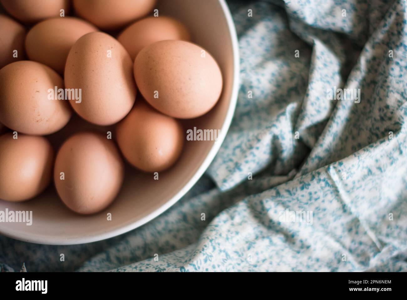 gros plan d'œufs bruns dans un bol blanc sur tissu floral Banque D'Images