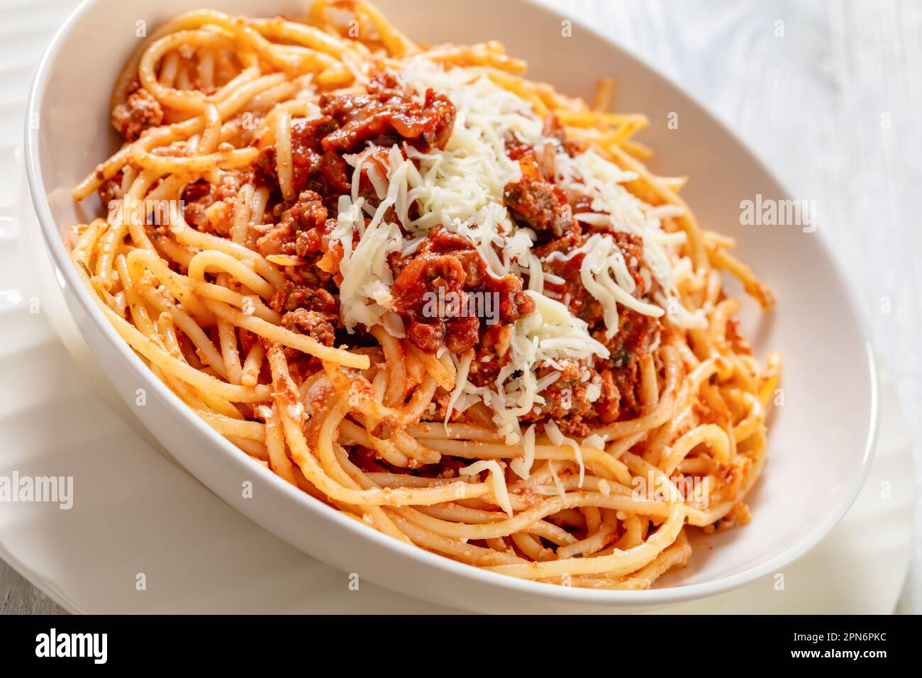 Spaghetti al ragu alla Bolognese, nappés de fromage râpé dans un bol blanc sur une table en bois blanc, vue en grand angle, gros plan Banque D'Images