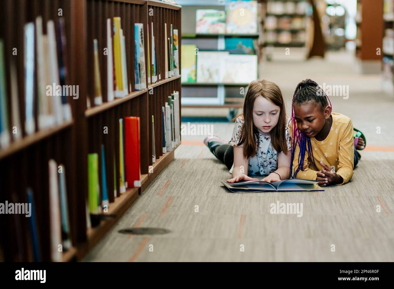 Deux jeunes filles lisant un livre à l'étage de la bibliothèque Banque D'Images