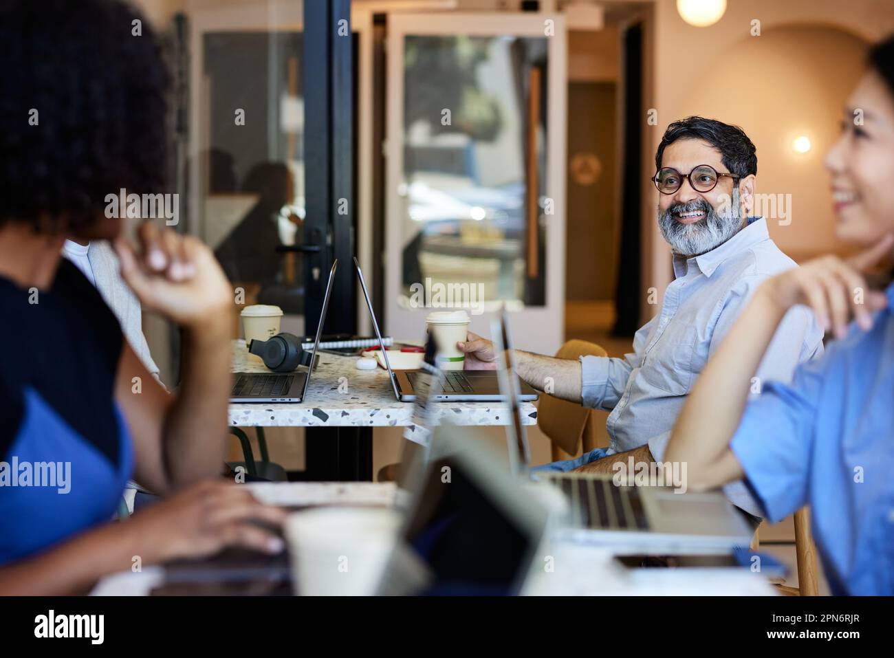 Un homme d'affaires mûr heureux discutant avec des collègues assis dans un café Banque D'Images