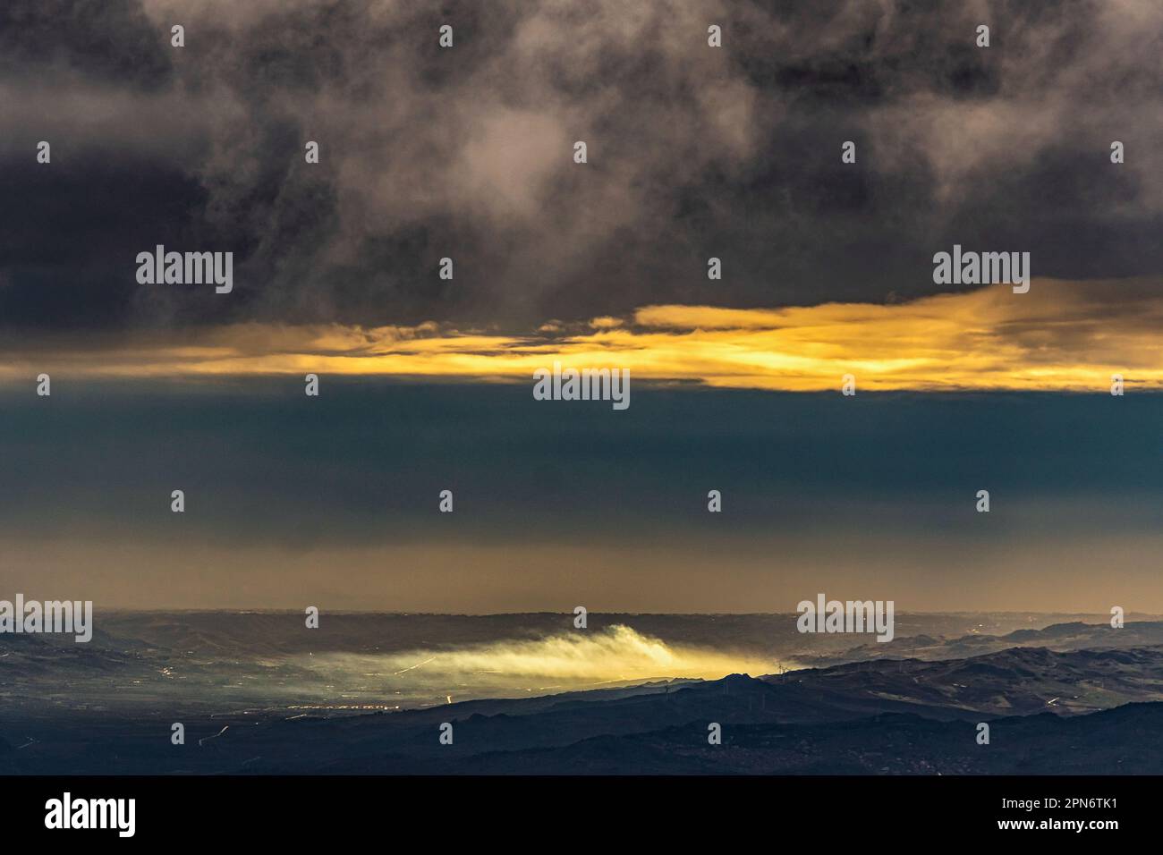 Une lumière chaude de l'aube illumine les nuages bas et la brume au-dessus de la ville de Catane et de son golfe. Sicile, Italie, Europe Banque D'Images