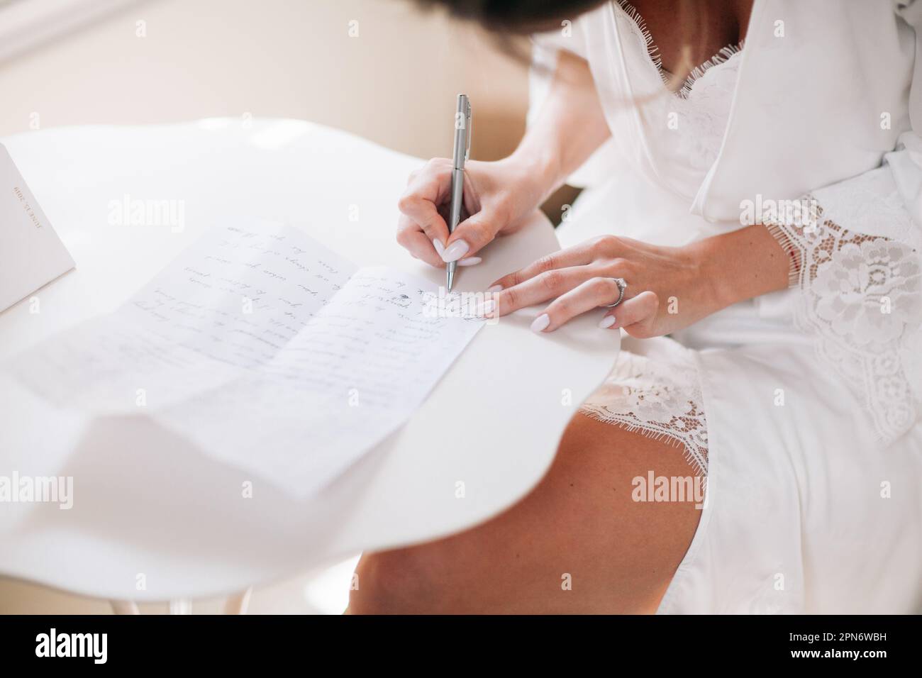 mariée écrivant une lettre le matin au mariage Banque D'Images