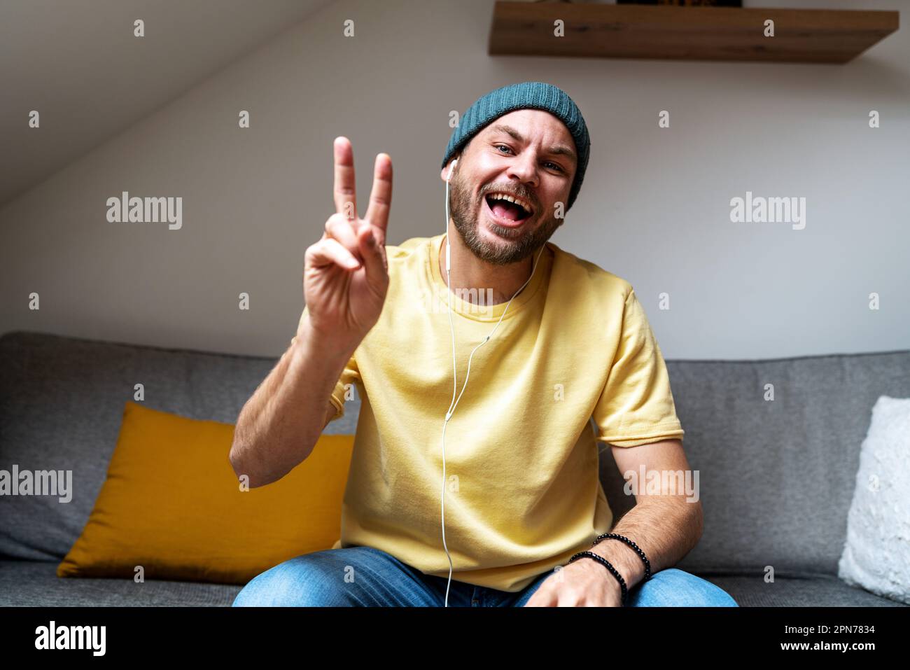 Homme gestuelle avec sa main avec le signe de paix devant la caméra pendant la conférence web en ligne, saluant les participants. Banque D'Images