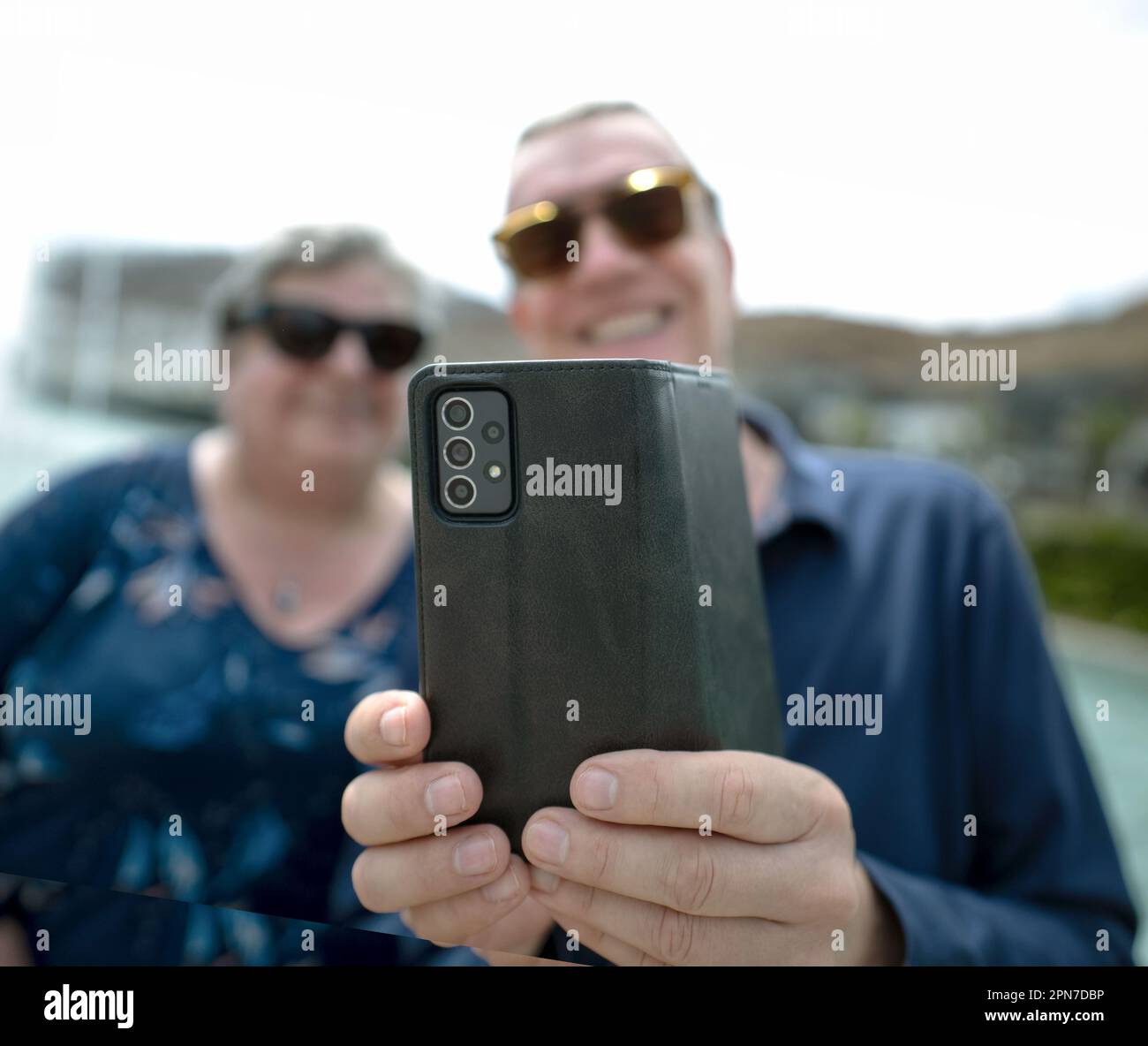 Femme et homme souriant, à l'extérieur, regardant l'affichage de téléphone cellulaire, bokeh Banque D'Images