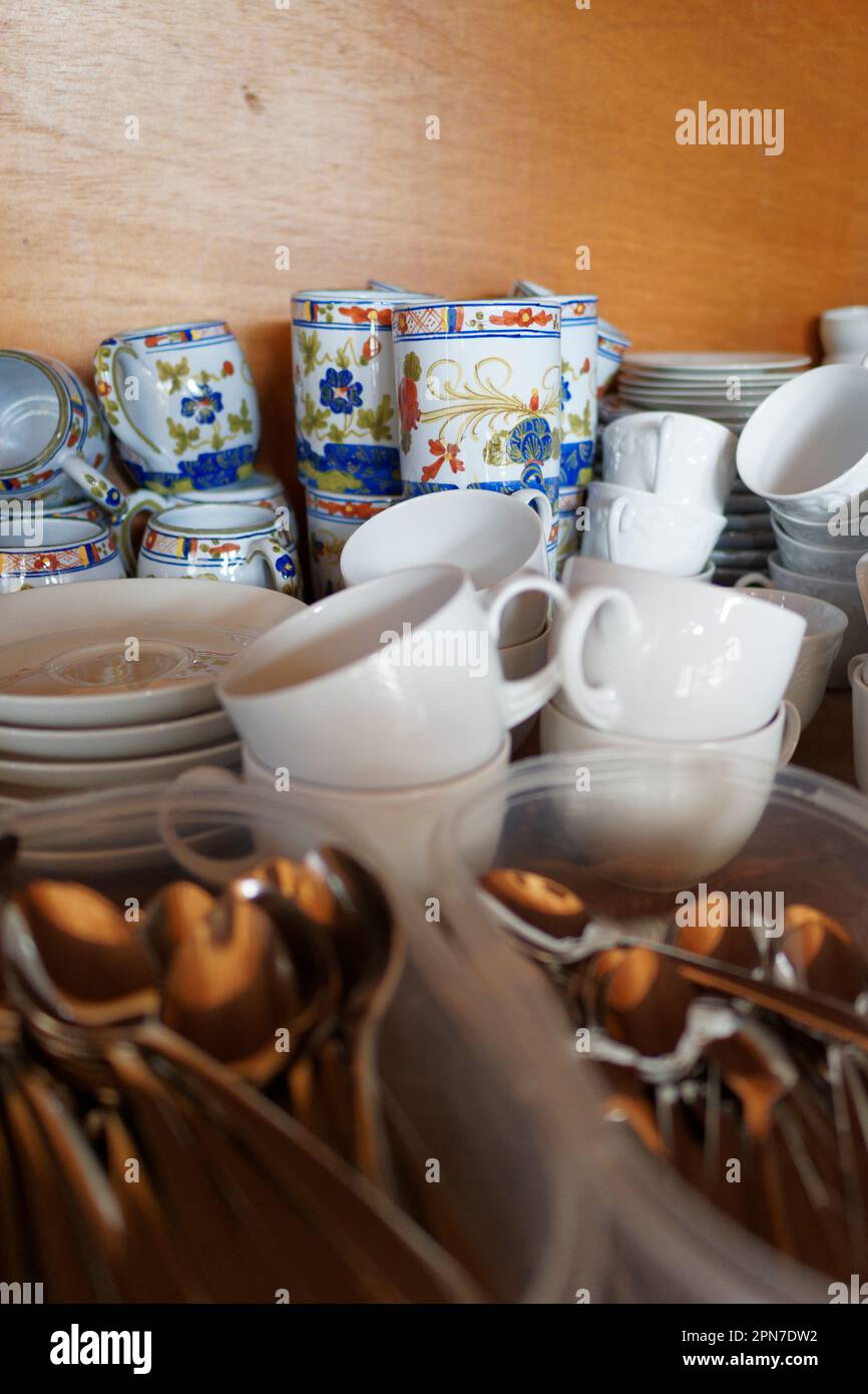 Diverses tasses dans un placard avec des cuillères à thé au premier plan Banque D'Images