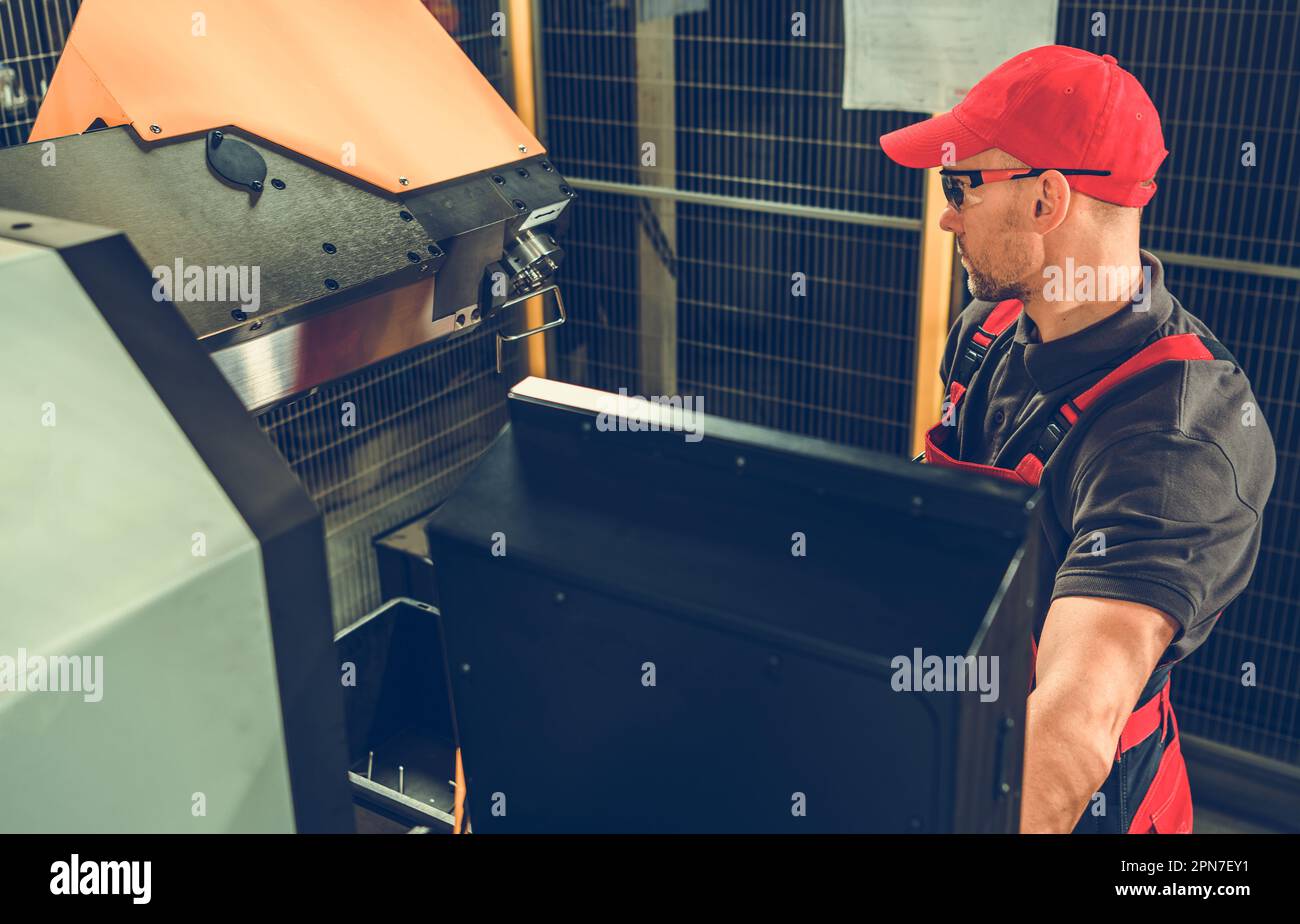 Machiniste caucasien professionnel en fonctionnement uniforme rouge de machine industrielle à l'usine de fabrication. Banque D'Images