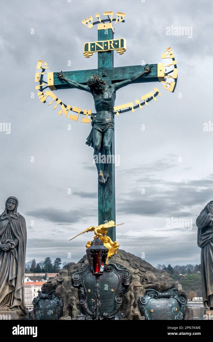 Prague, Tchéquie - 03.24.2023: Crucifix de bronze avec des lettres d'or. Pont Charles, Prague. Monument chrétien historique dans le centre de Prague Banque D'Images