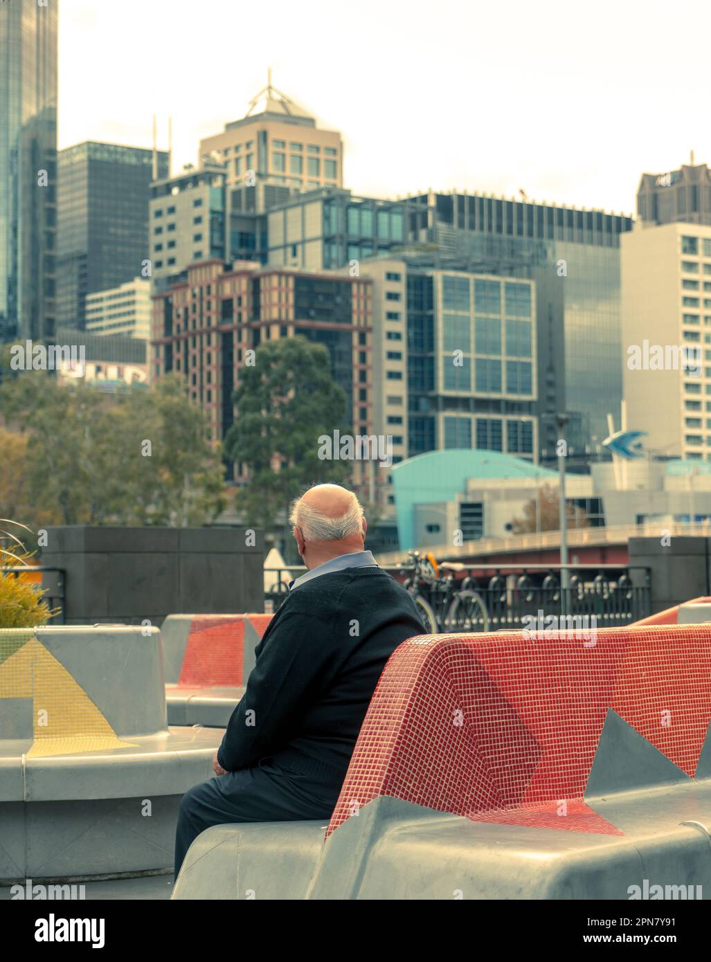 Melbourne, Australie - vieil homme assis sur un banc de béton et regardant les gratte-ciel de la ville Banque D'Images