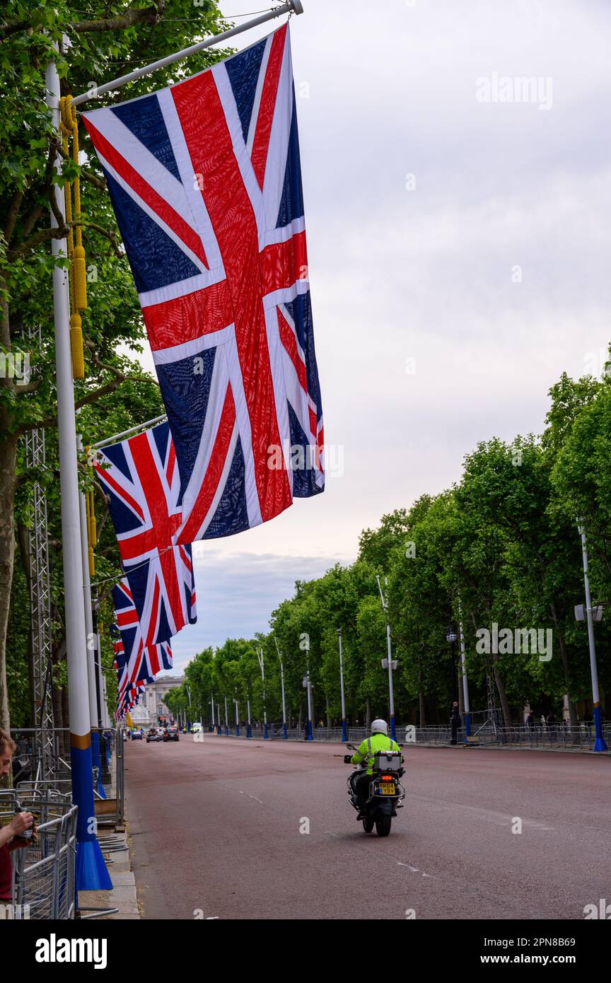 LONDRES - 18 mai 2022 : les drapeaux de l'Union Jack surpassent le centre commercial, ajoutant un esprit patriotique aux célébrations du Jubilé de platine, lorsqu'un motocycliste passe. Banque D'Images