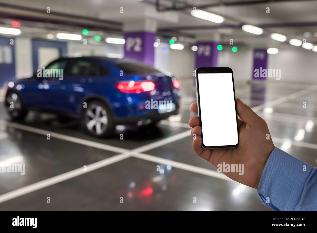 Téléphone intelligent avec écran blanc à portée de main sur l'arrière-plan du parking Banque D'Images