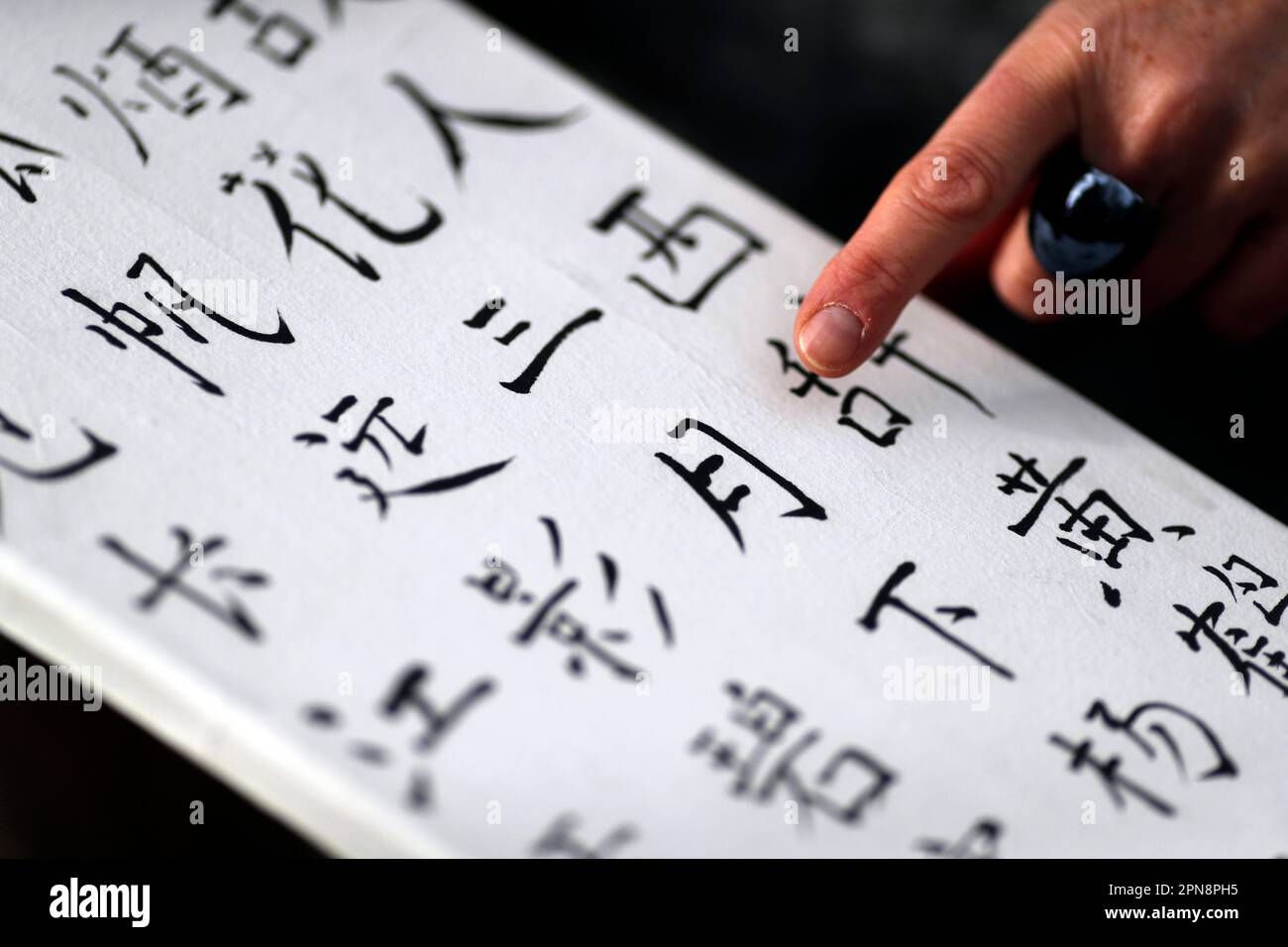 Femme montrant son travail avec des caractères chinois. Calligraphie chinoise. France. Banque D'Images