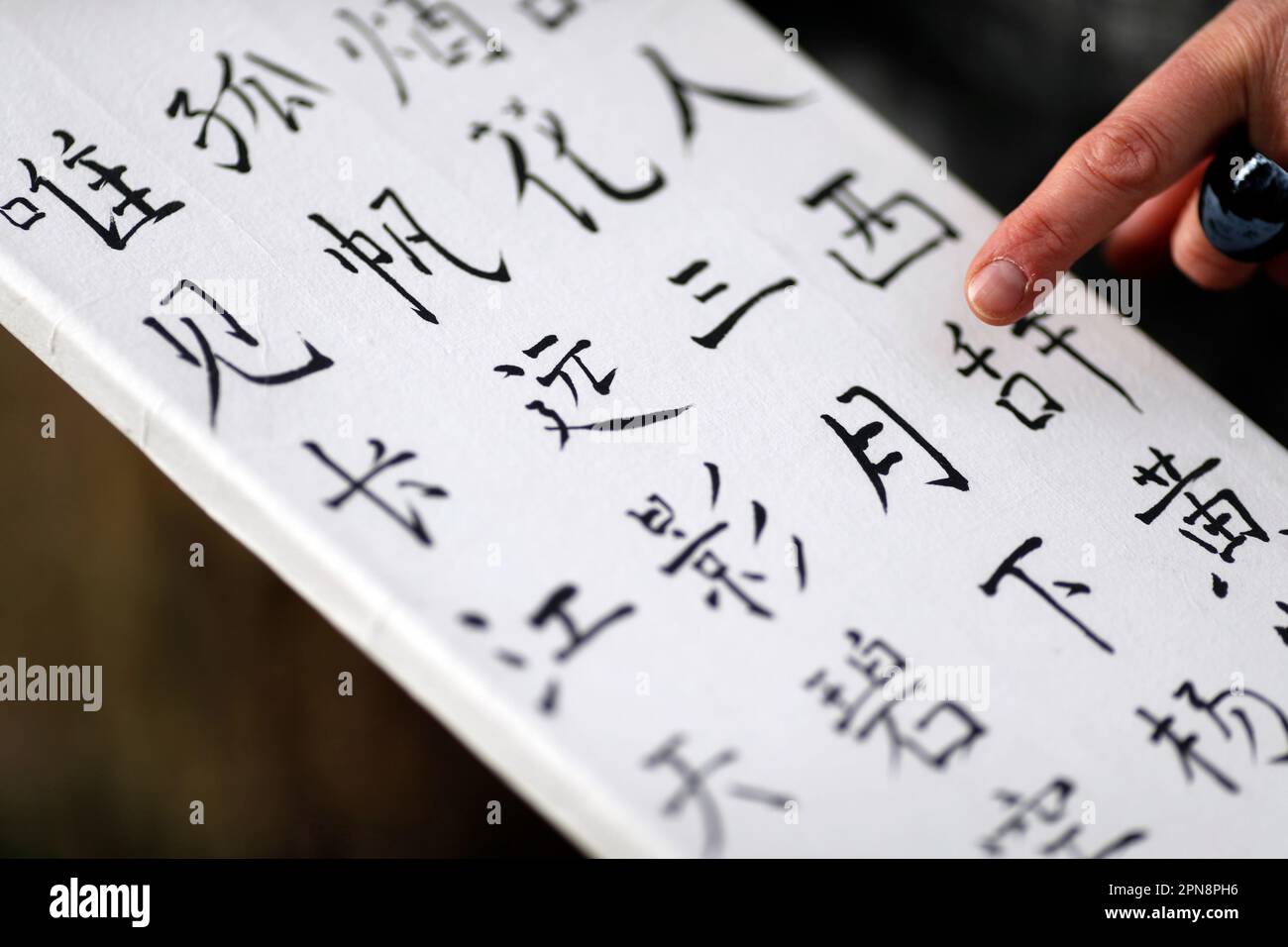 Femme montrant son travail avec des caractères chinois. Calligraphie chinoise. France. Banque D'Images