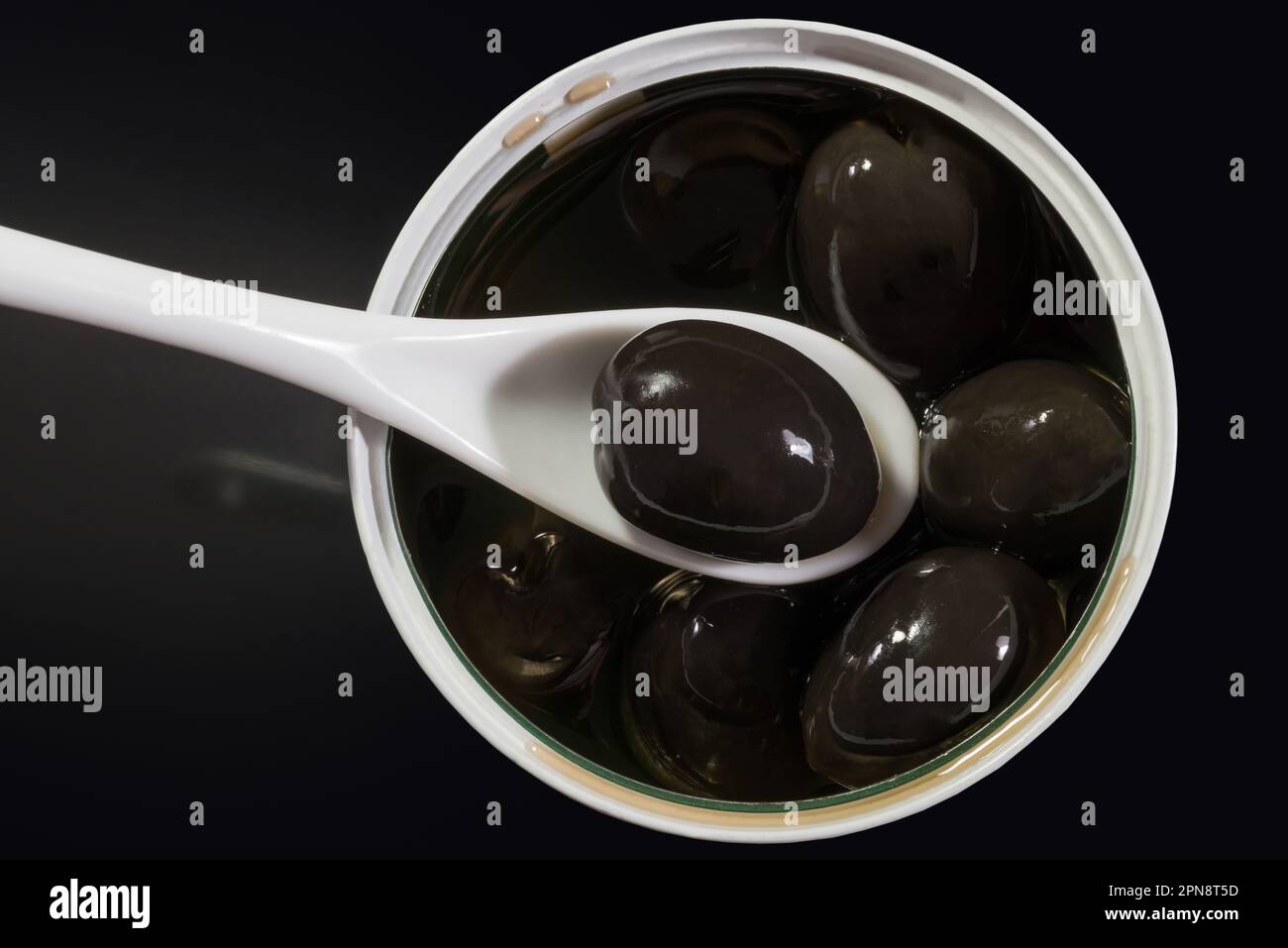 Olive noire en cuillère sur l'assiette avec tas d'olives noires dans l'huile Banque D'Images