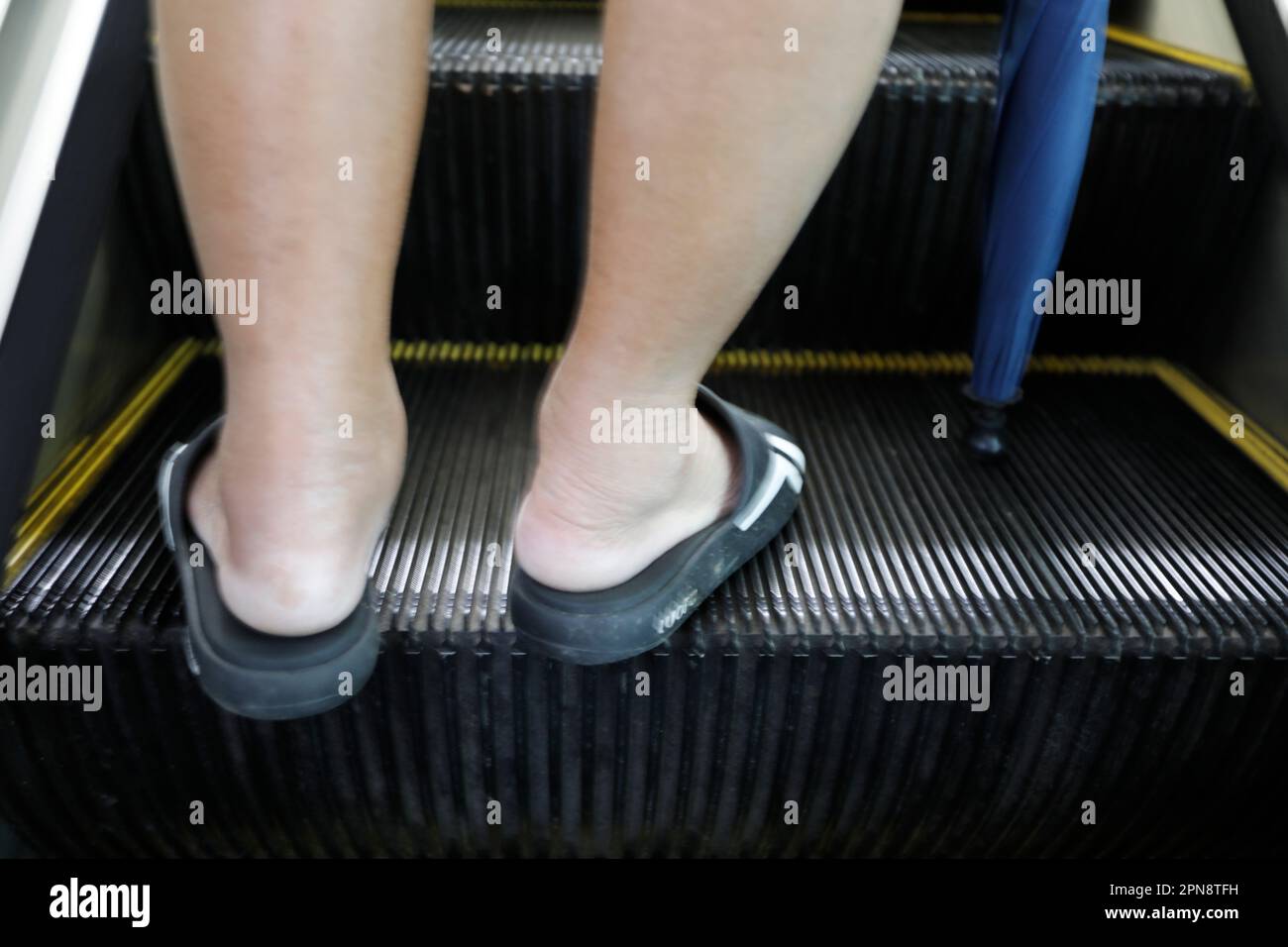 Centre commercial. Un homme sur un escalier mécanique. Gros plan sur les pieds. Singapour. Banque D'Images