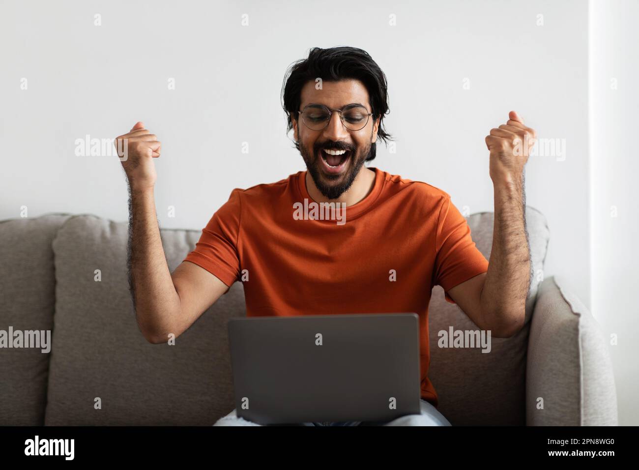 Joyeux et excités jeune homme moyen-oriental avec bouche ouverte et ordinateur  portable fait le geste de la victoire Photo Stock - Alamy