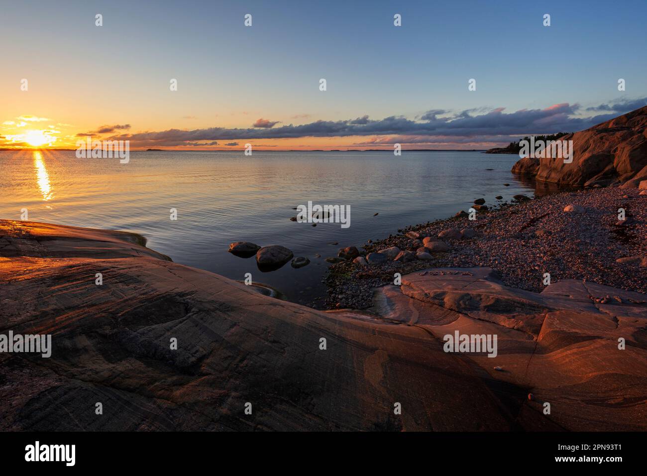 Belle vue sur la plage de galets rocheux, la falaise et la mer Baltique à Hanko, en Finlande, au coucher du soleil en été. Banque D'Images